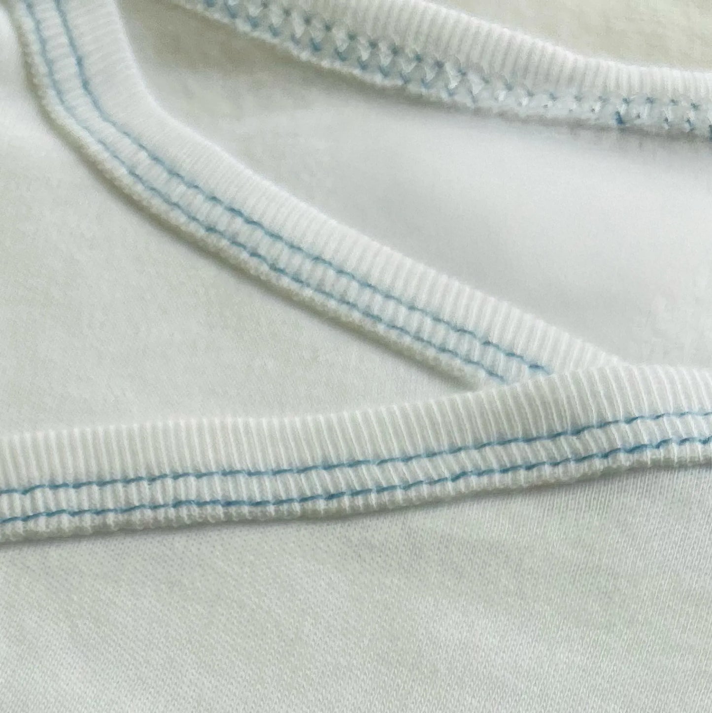 Pormenor de body de trespasse cardado com ursinho bordado em ponto de cruz azul