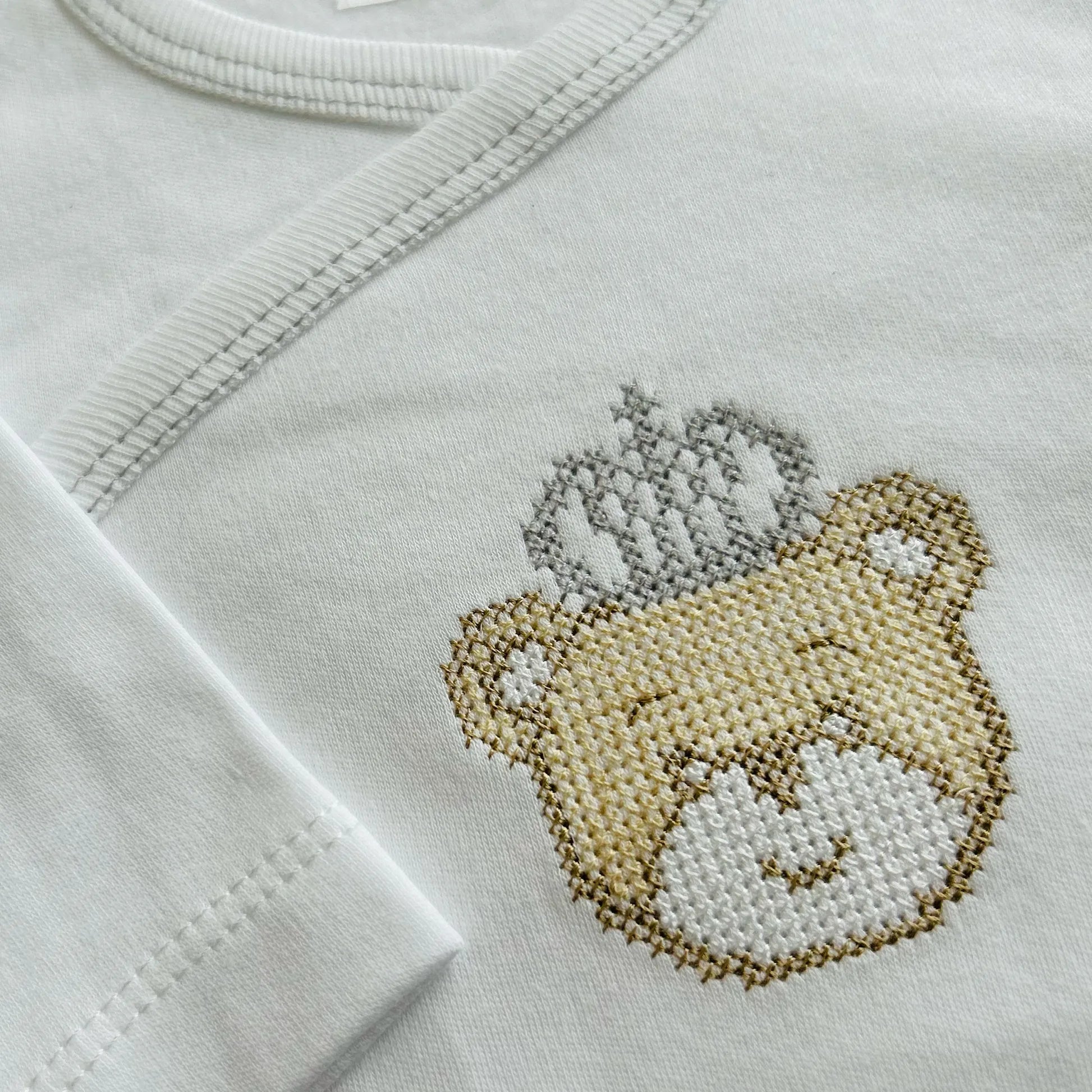 Pormenor de body de trespasse cardado com ursinho bordado em ponto de cruz cinza