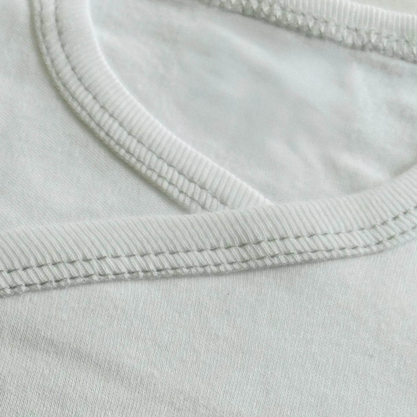 Pormenor de body de trespasse cardado com ursinho bordado em ponto de cruz cinza