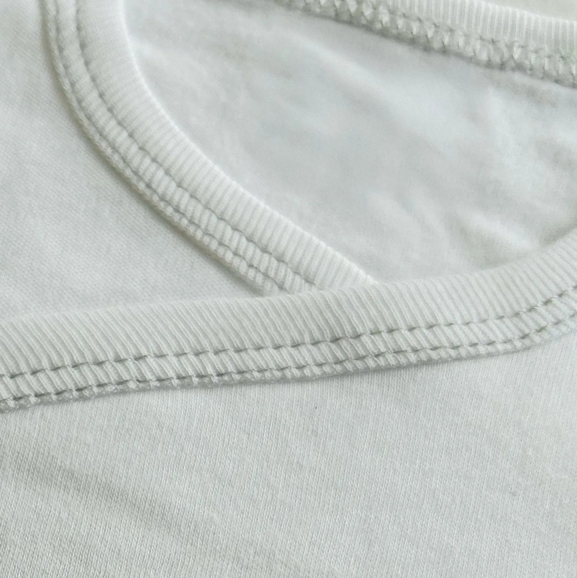 Pormenor de body de trespasse cardado com ursinho bordado em ponto de cruz cinza