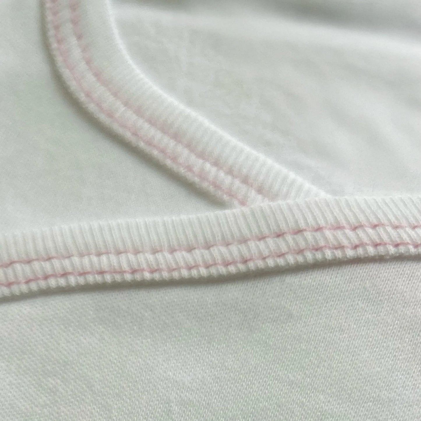 Pormenor de body de trespasse cardado com ursinho bordado em ponto de cruz rosa