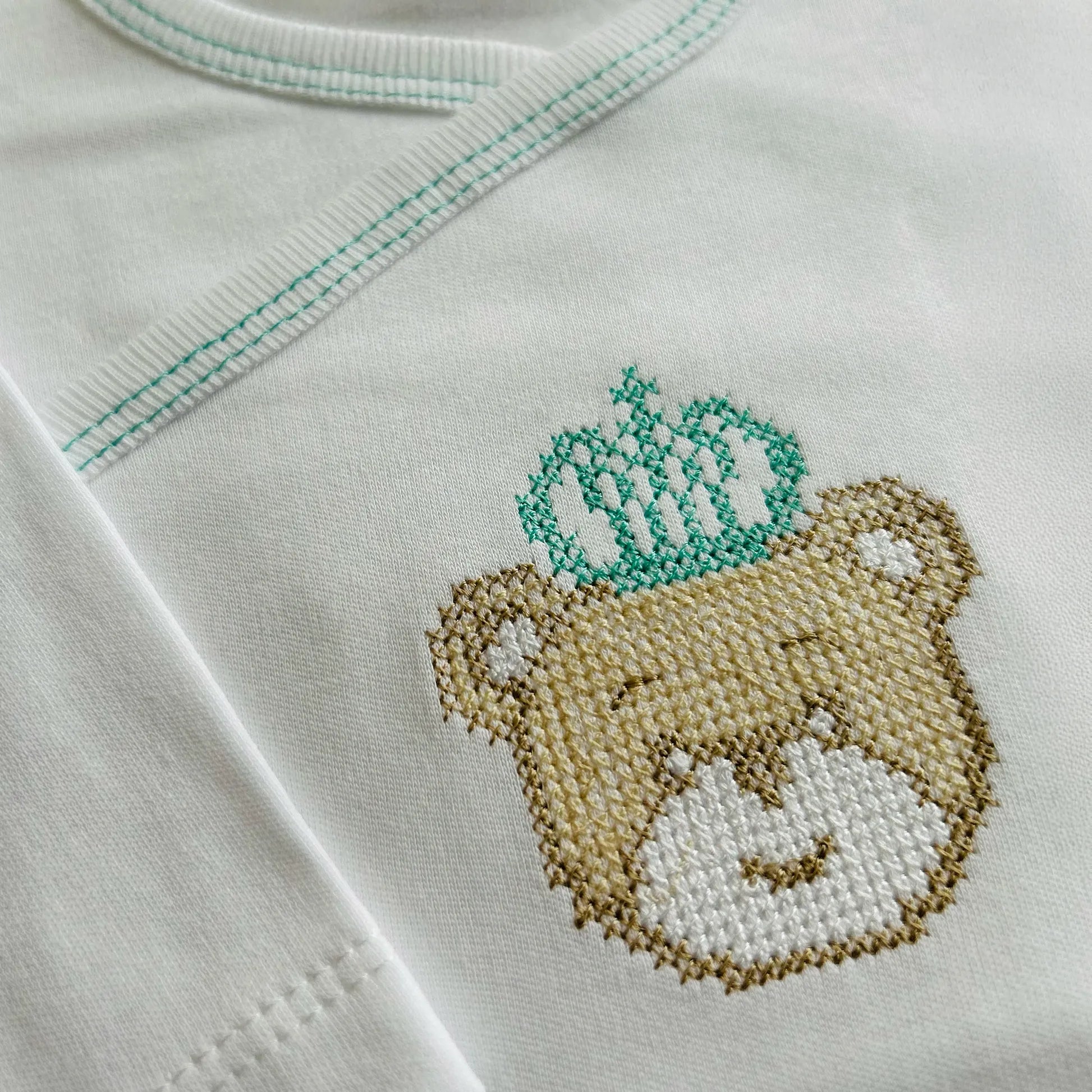 Pormenor de body de trespasse cardado com ursinho bordado em ponto de cruz verde