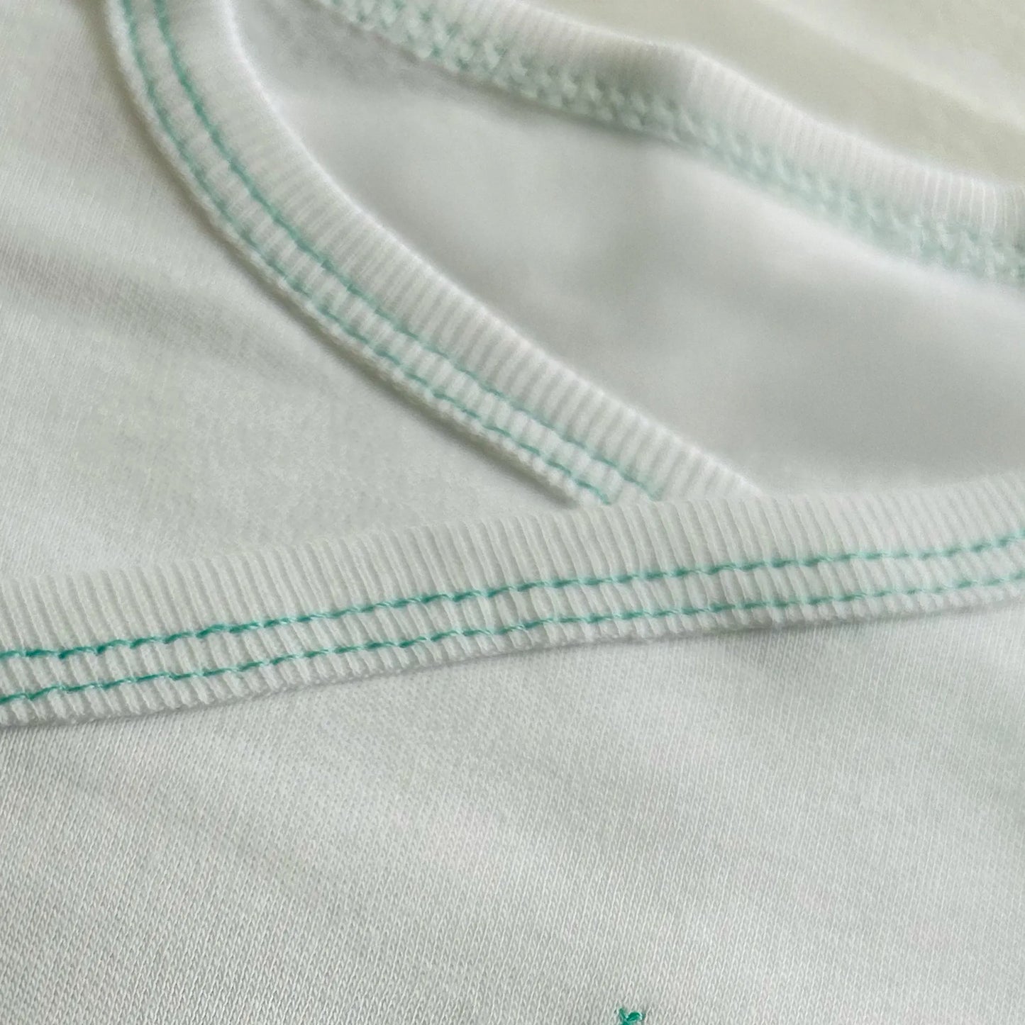 Pormenor de body de trespasse cardado com ursinho bordado em ponto de cruz verde