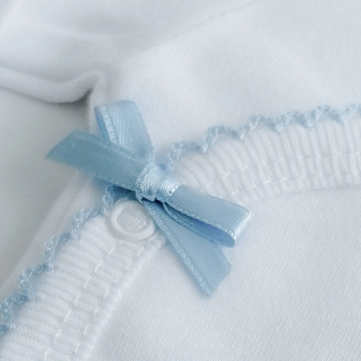 Pormenor de body de trespasse com collant cardado com bordado em redor azul