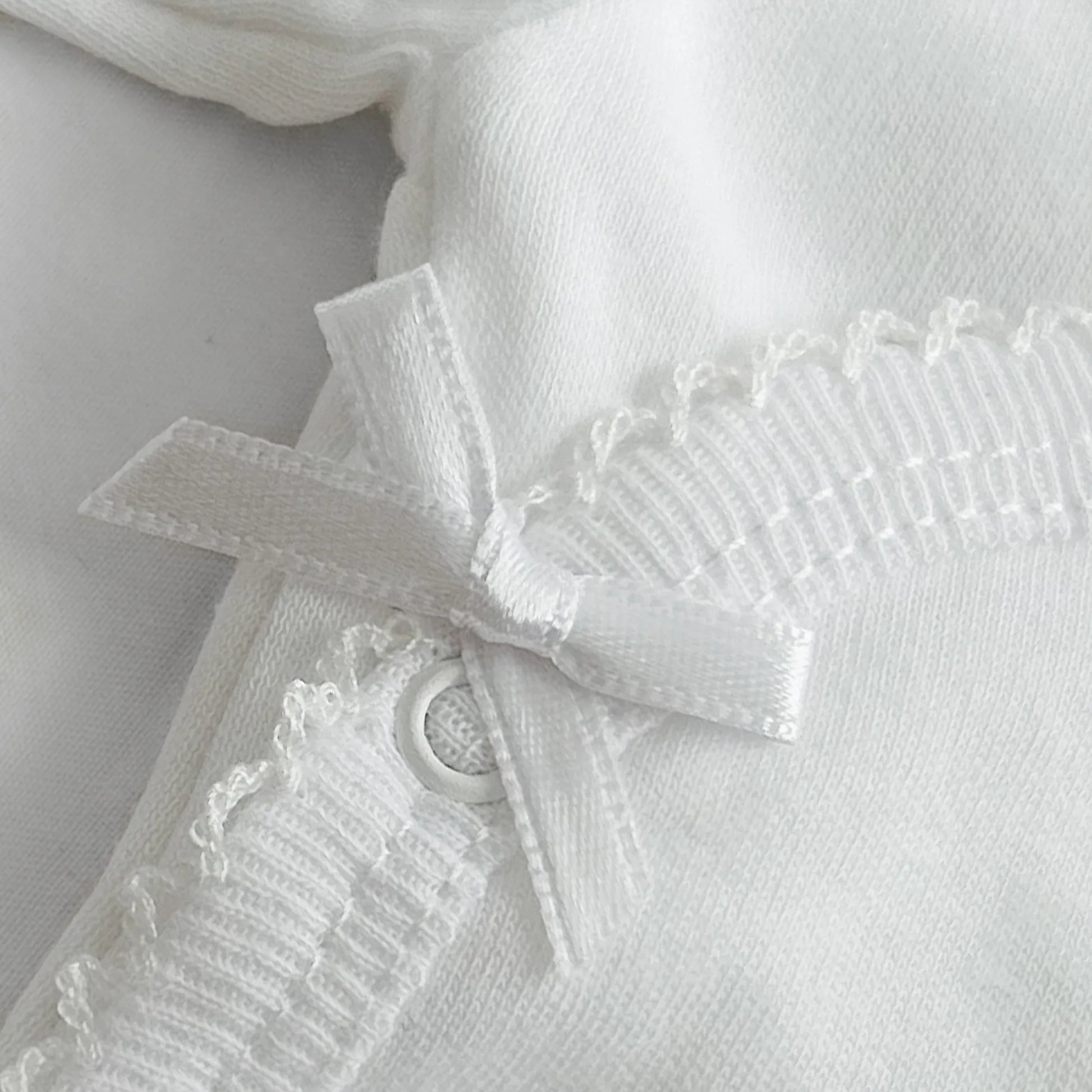 Pormenor de body de trespasse com collant cardado com bordado em redor branco