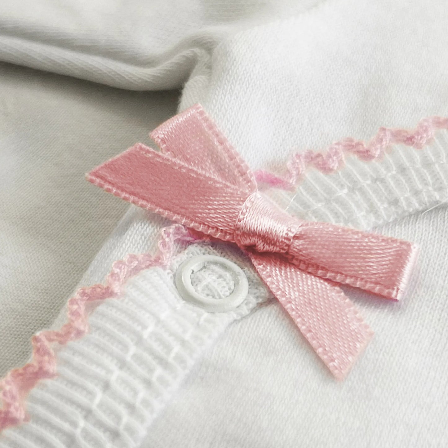 Pormenor de body de trespasse com collant cardado com bordado em redor rosa