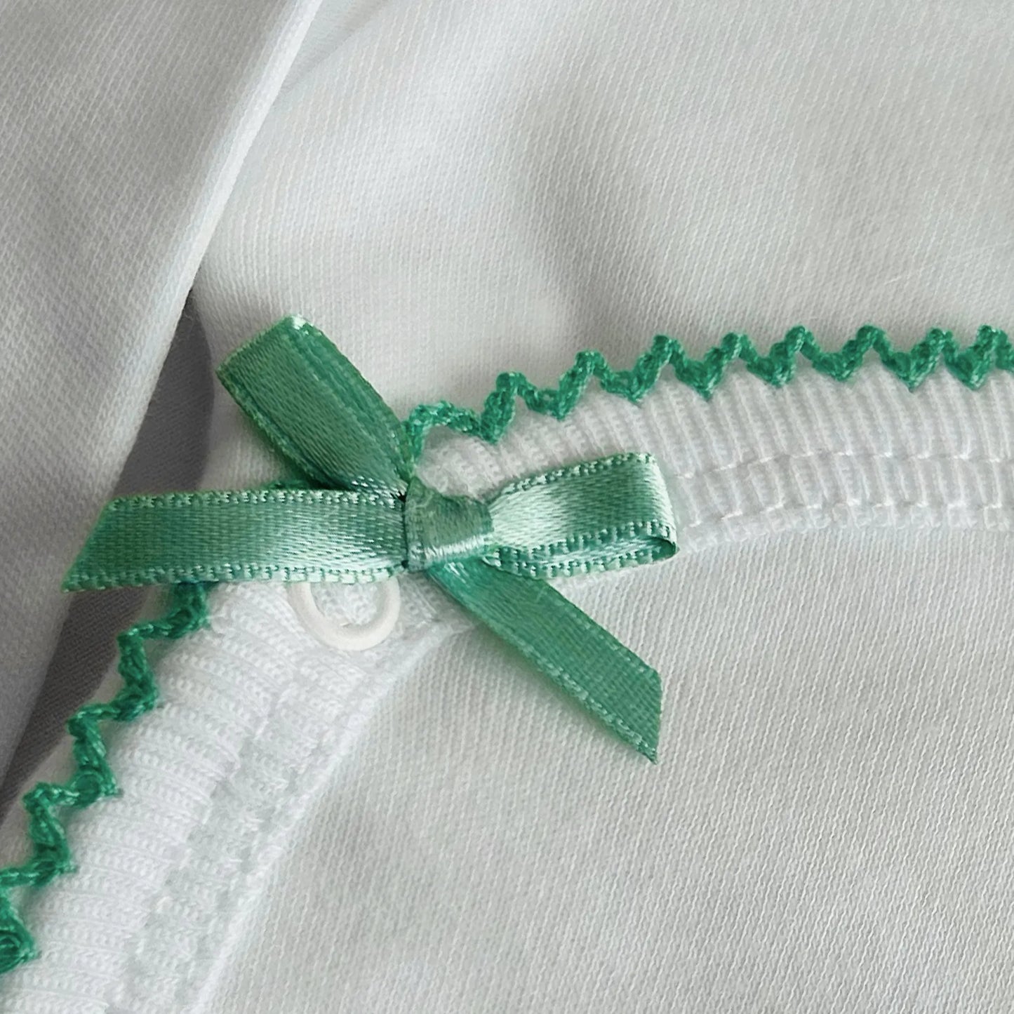 Pormenor de body de trespasse com collant cardado com bordado em redor verde