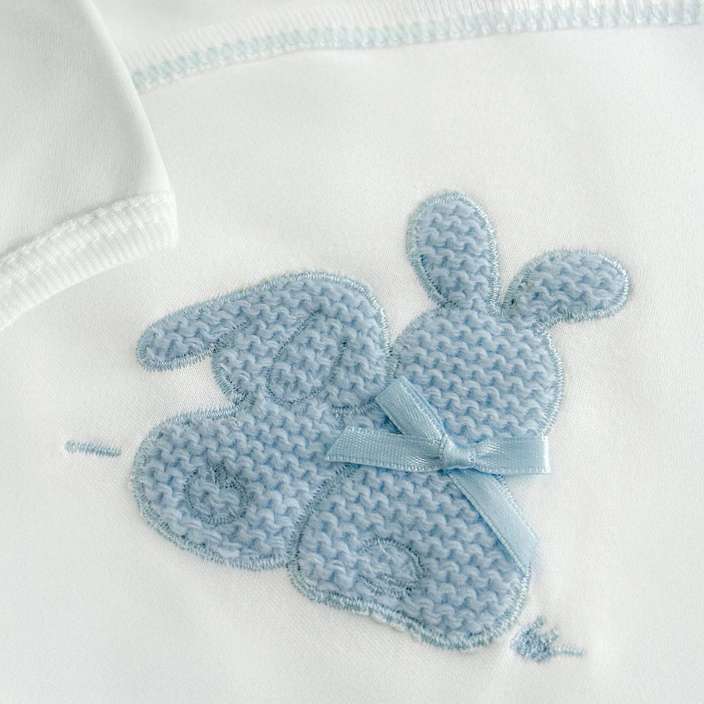 Pormenor de body de trespasse com collant cardado com motivo coelhos tricot com lacinho azul