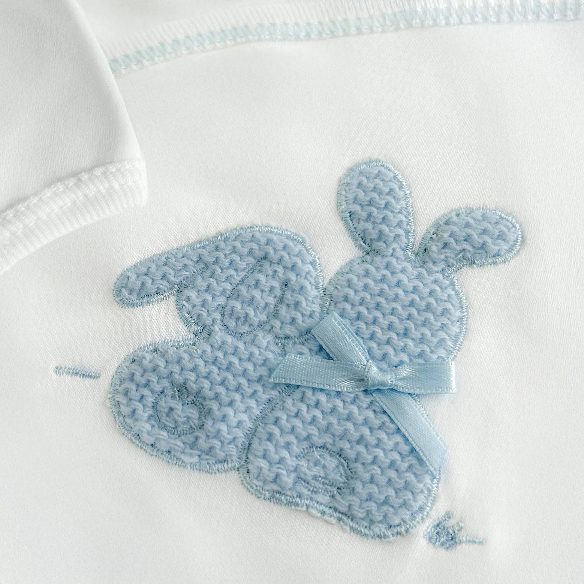 Pormenor de body de trespasse com collant cardado com motivo coelhos tricot com lacinho azul