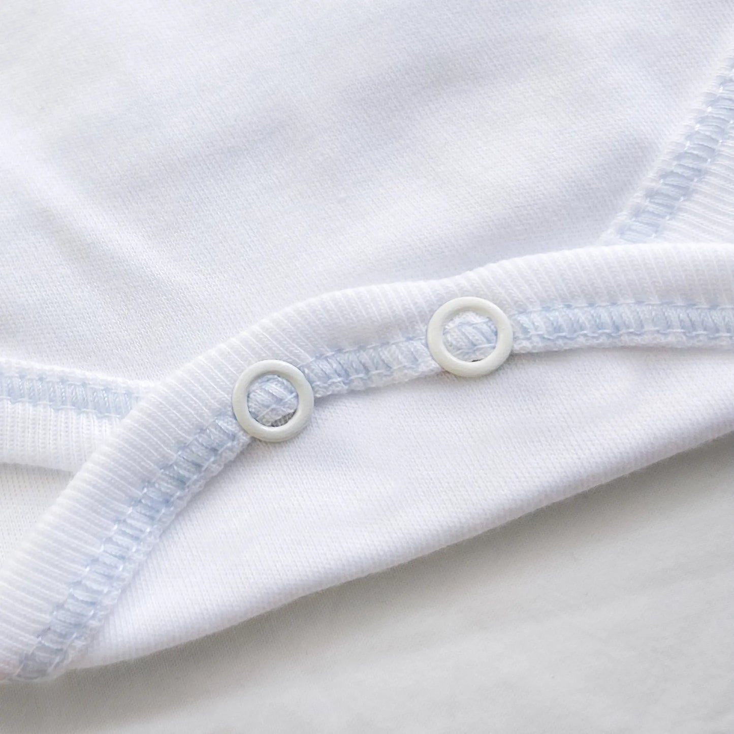 Pormenor de body de trespasse com collant cardado com motivo coelhos tricot com lacinho azul