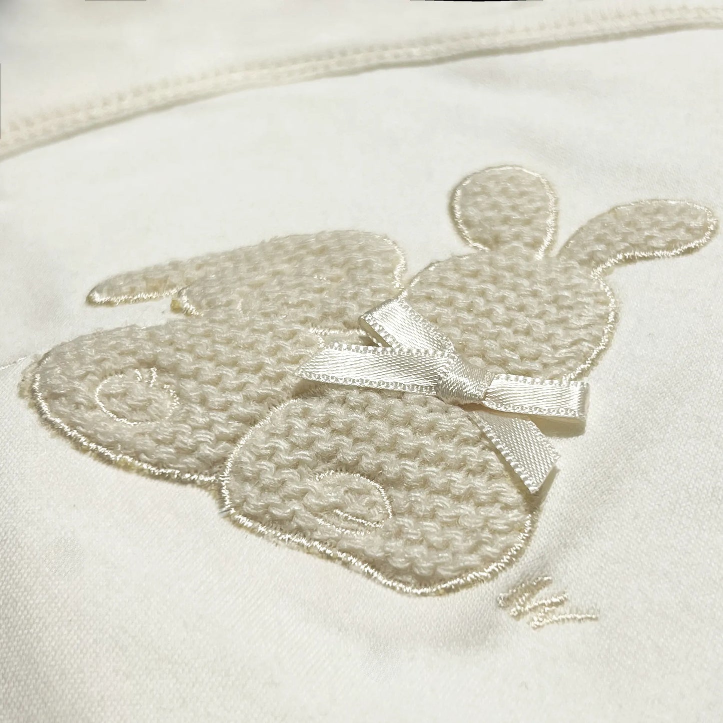 Pormenor de body de trespasse com collant cardado com motivo coelhos tricot com lacinho bege