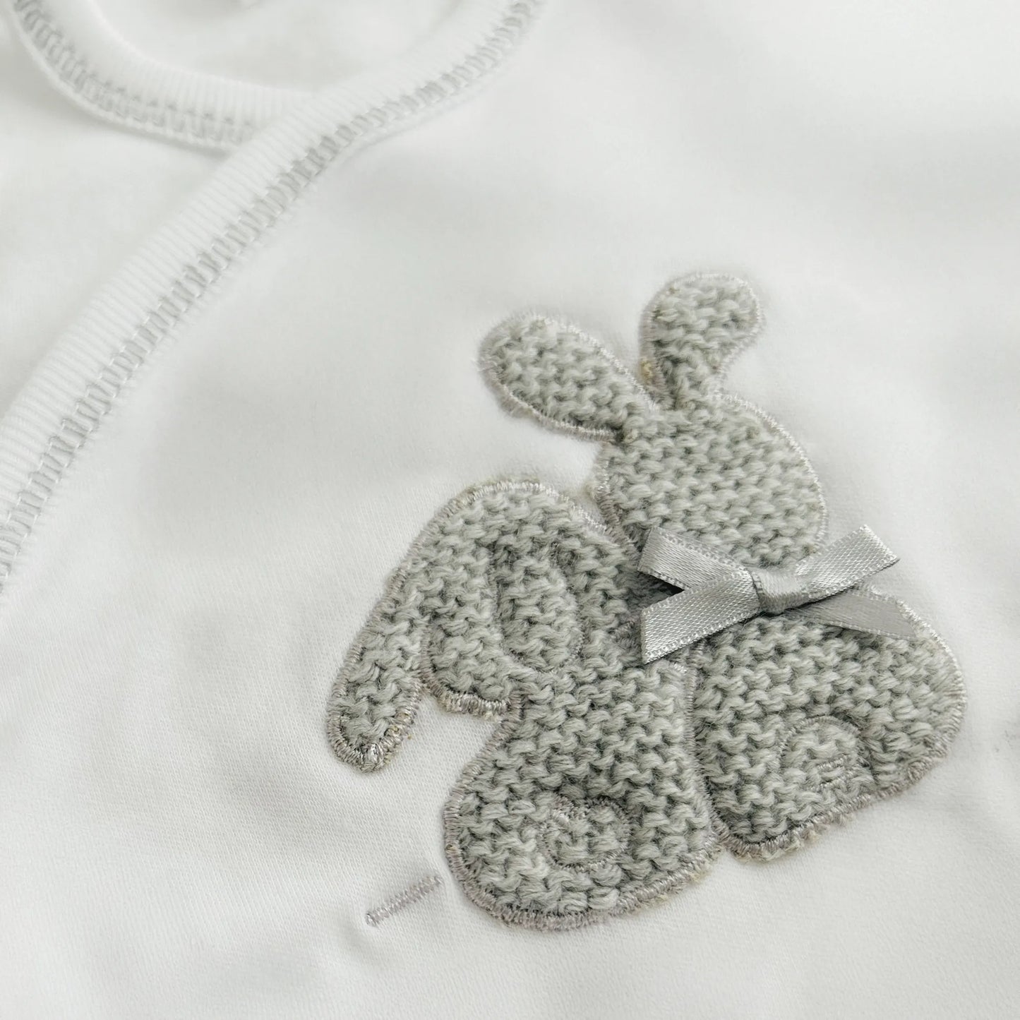 Pormenor de body de trespasse com collant cardado com motivo coelhos tricot com lacinho cinza