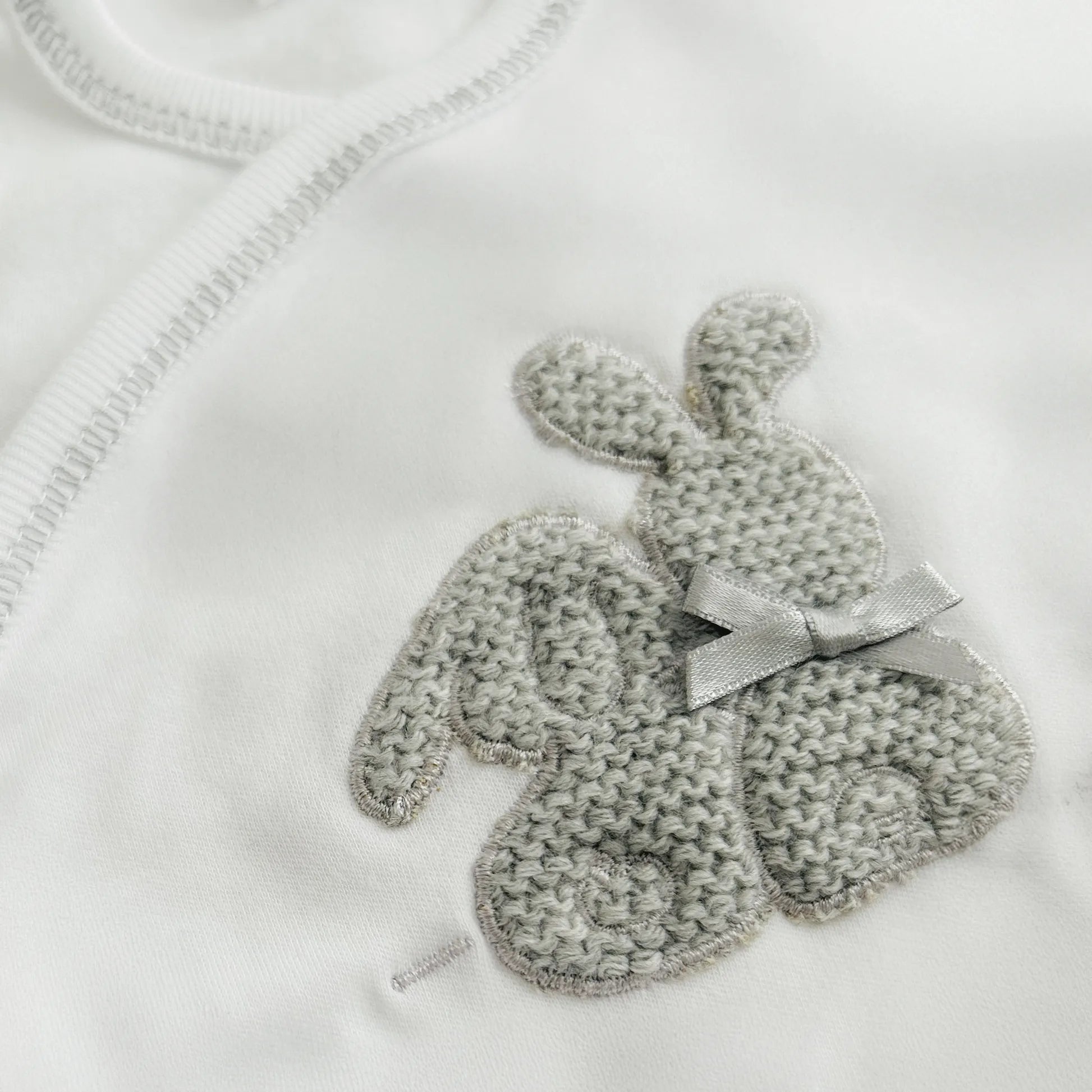 Pormenor de body de trespasse com collant cardado com motivo coelhos tricot com lacinho cinza