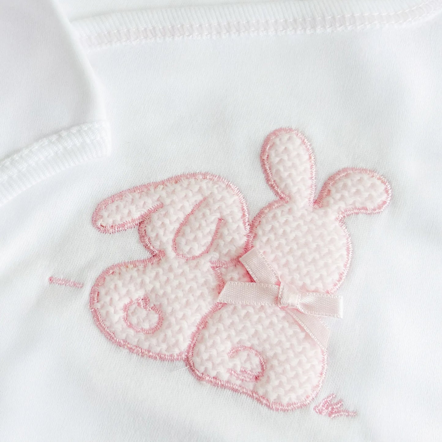 Pormenor de body de trespasse com collant cardado com motivo coelhos tricot com lacinho rosa