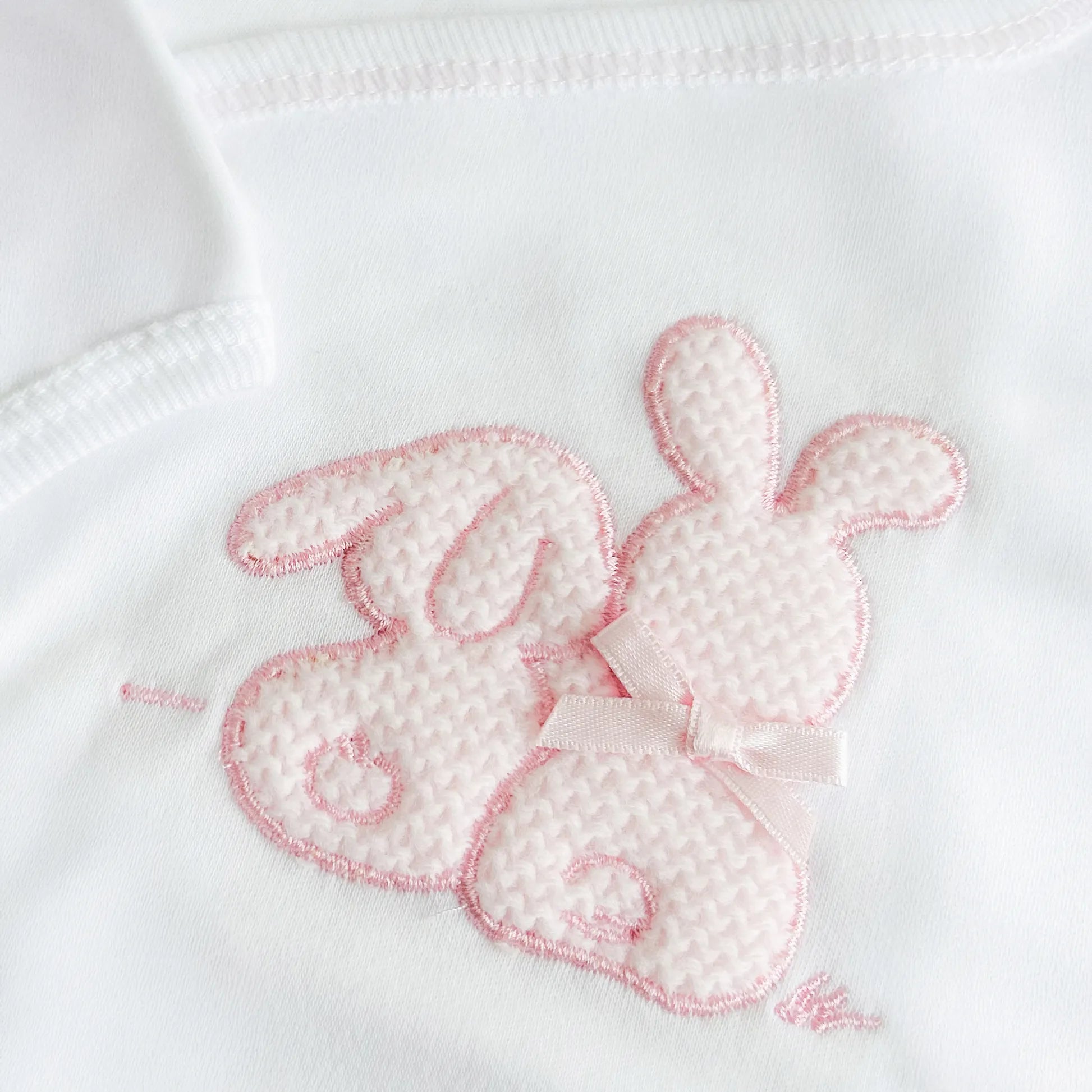 Pormenor de body de trespasse com collant cardado com motivo coelhos tricot com lacinho rosa