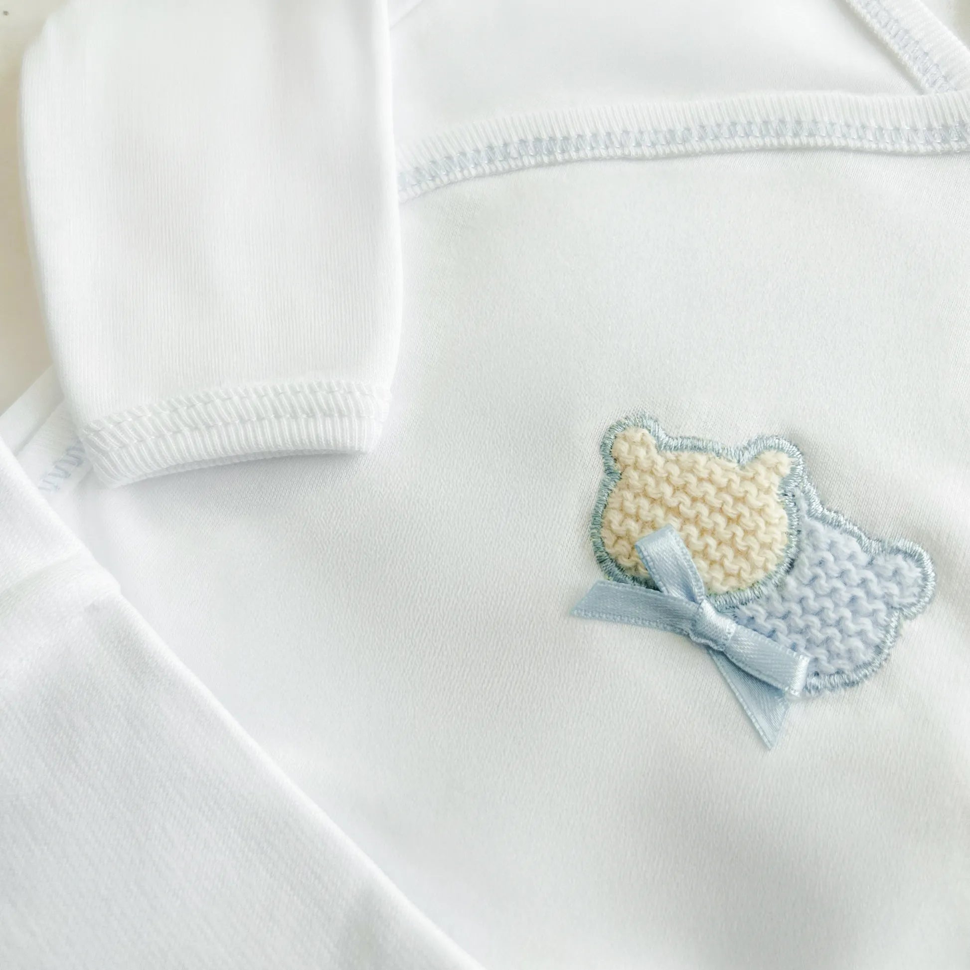 Pormenor de body de trespasse com collant cardado com motivo ursinhos tricot e lacinho azul