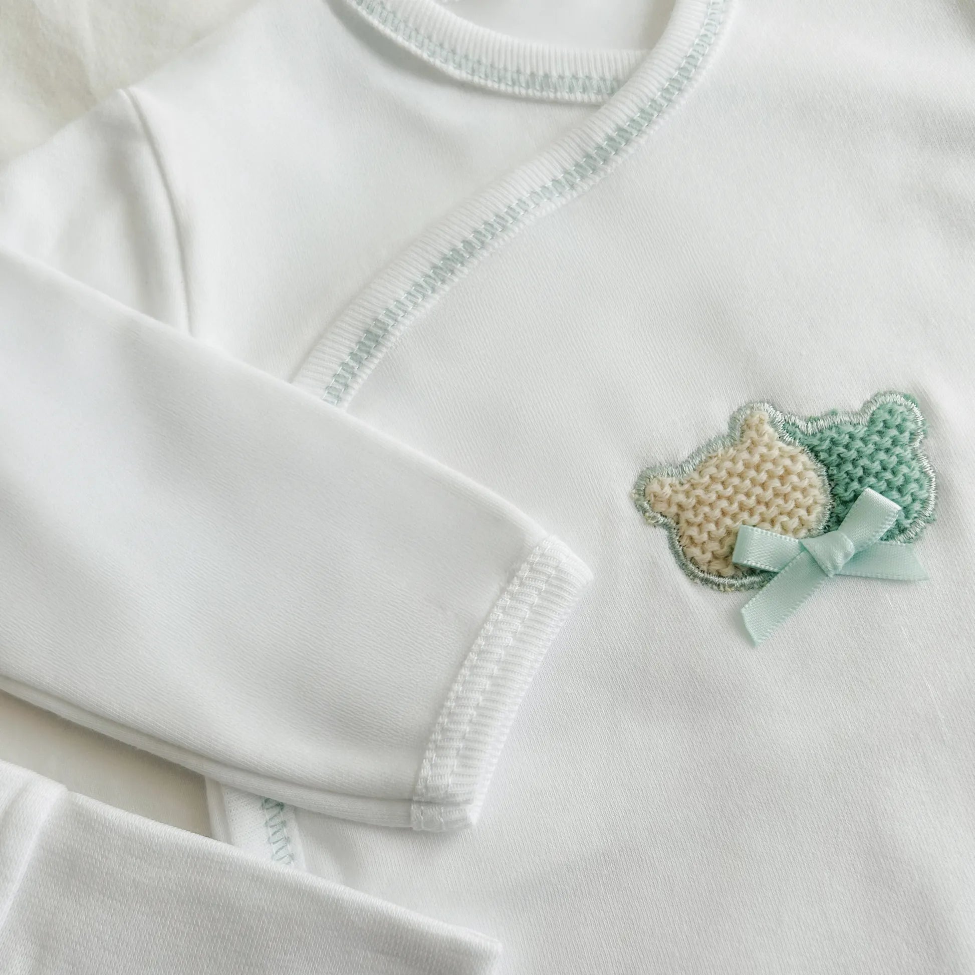 Pormenor de body de trespasse com collant cardado com motivo ursinhos tricot e lacinho verde