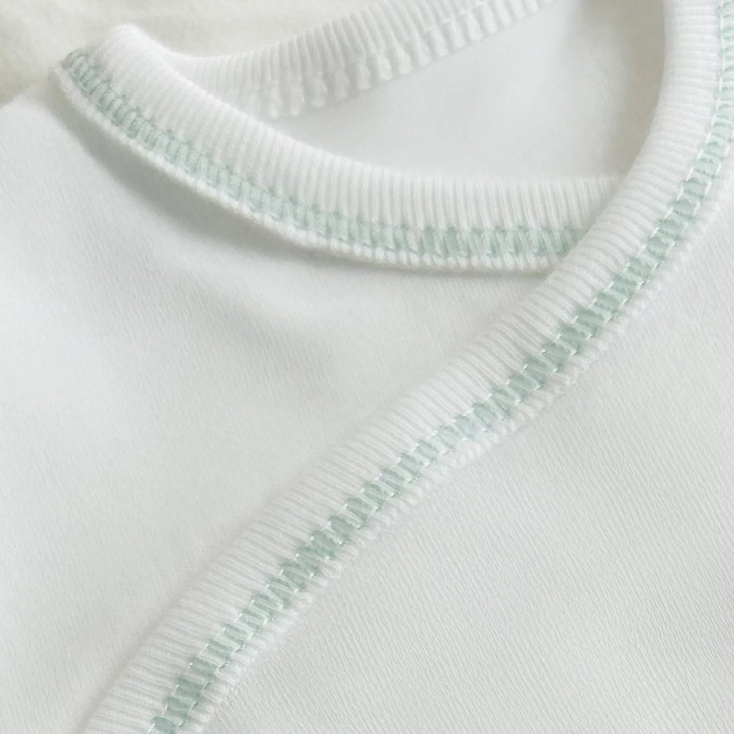 Pormenor de body de trespasse com collant cardado com motivo ursinhos tricot e lacinho verde