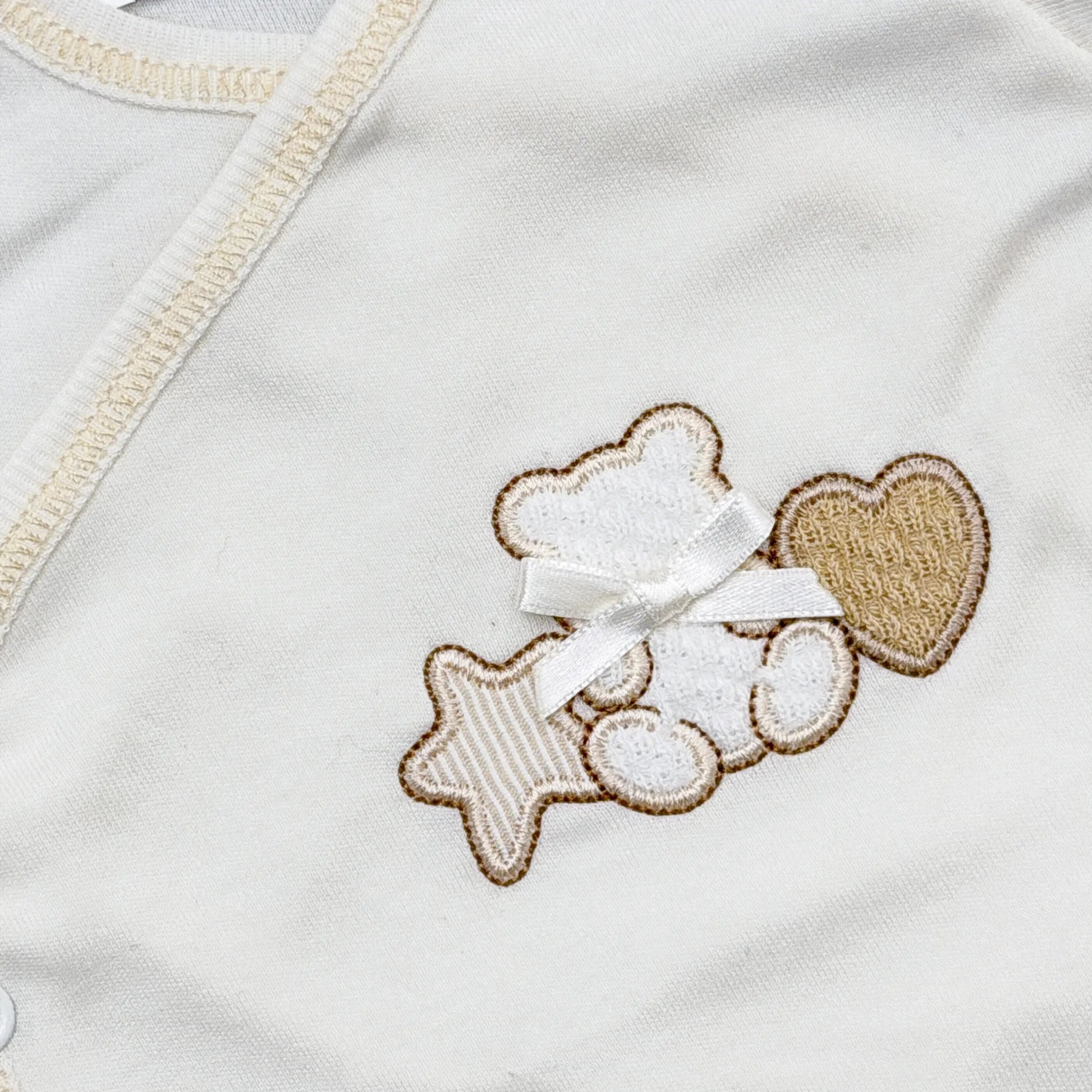 Pormenor de body de trespasse com collant com motivo ursinho entre estrela e coração pérola