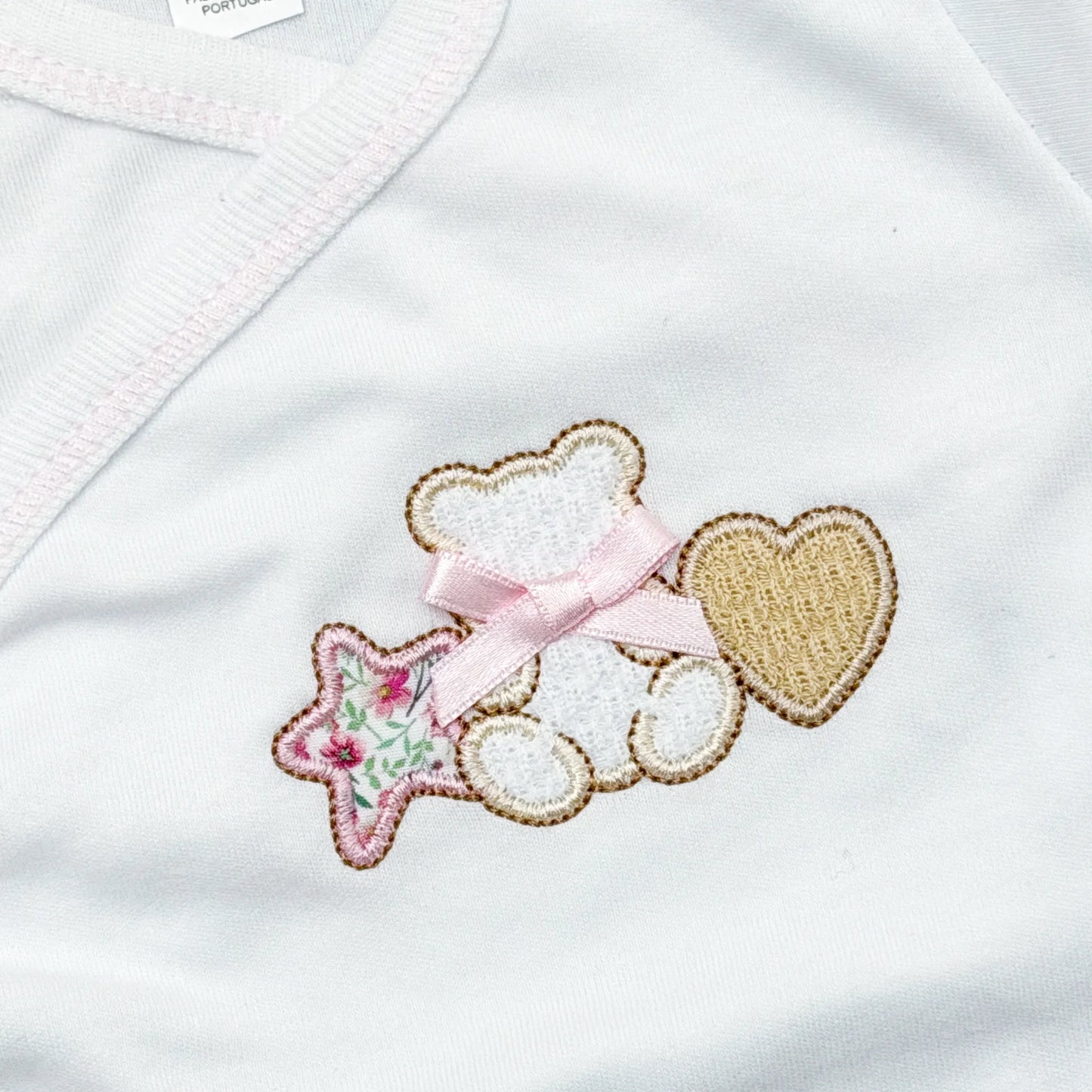 Pormenor de body de trespasse com collant com motivo ursinho entre estrela e coração rosa