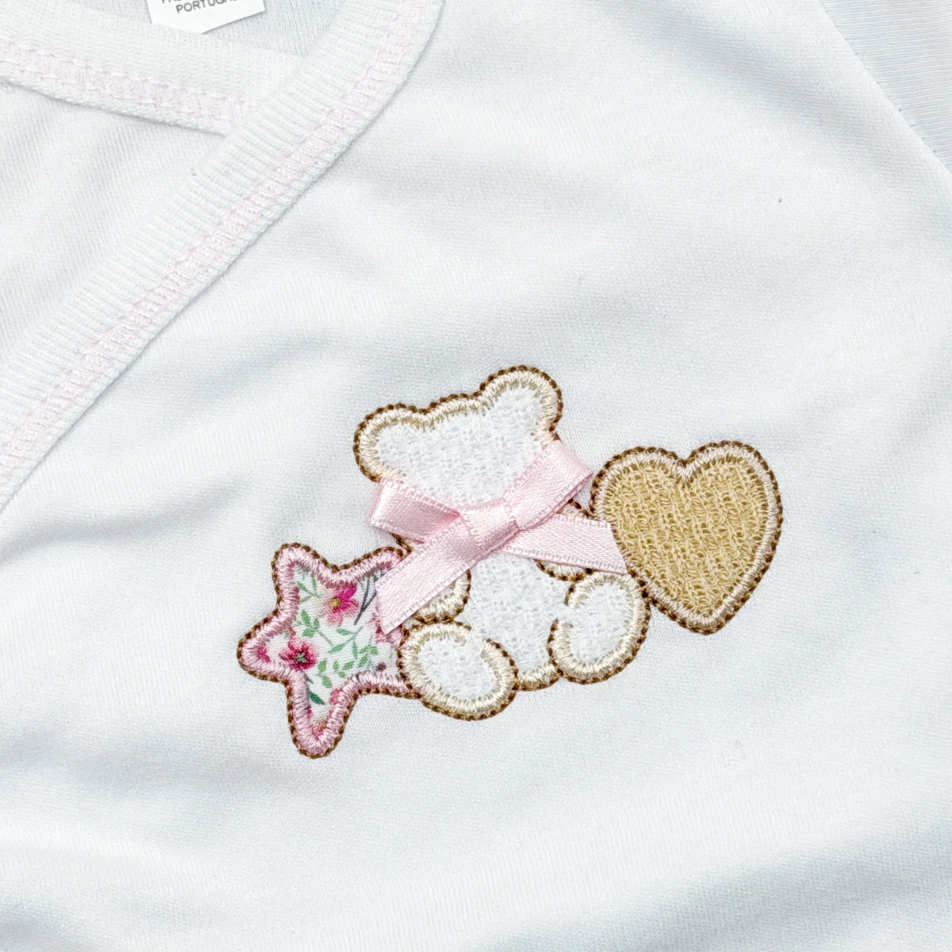 Pormenor de body de trespasse com collant com motivo ursinho entre estrela e coração rosa