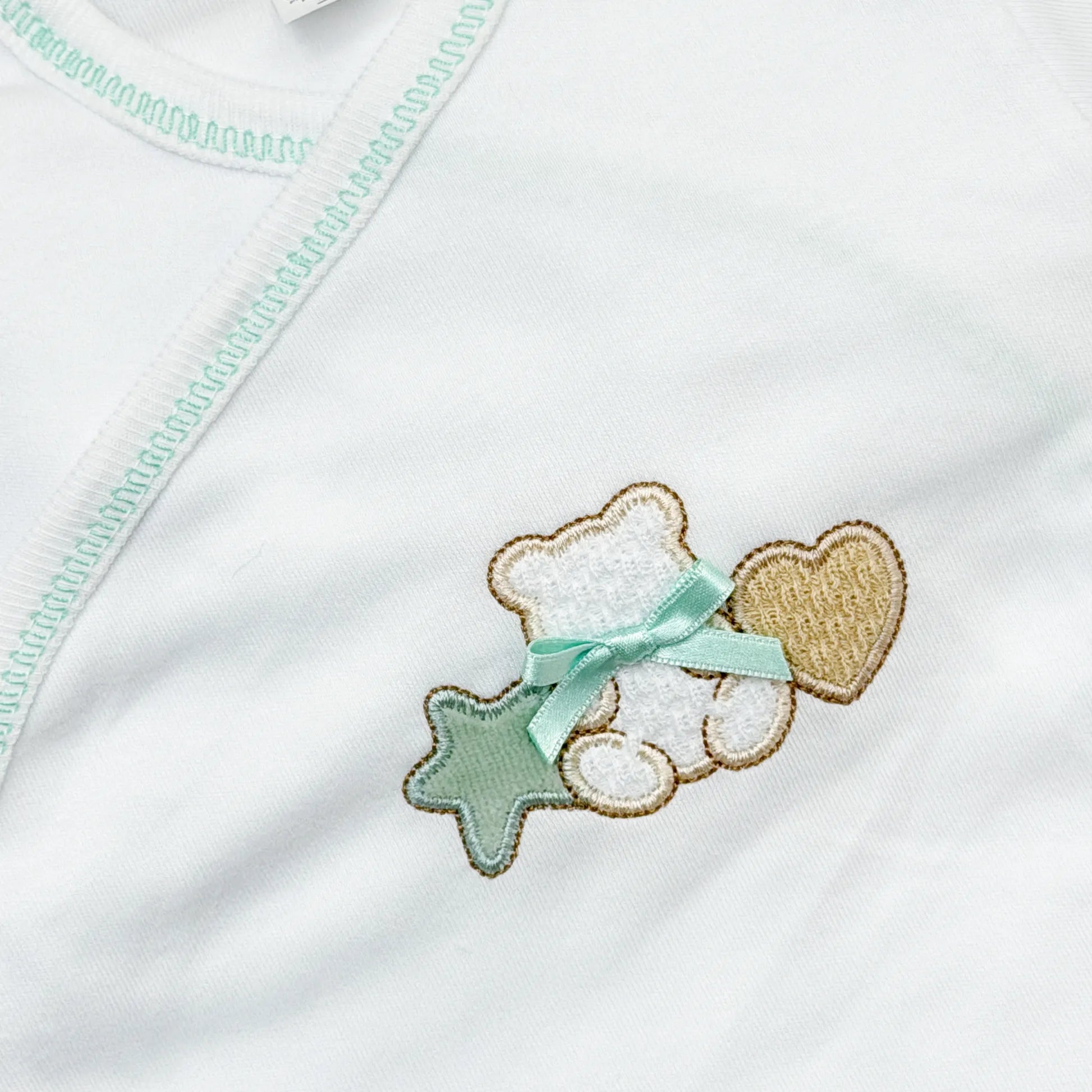 Pormenor de body de trespasse com collant com motivo ursinho entre estrela e coração verde