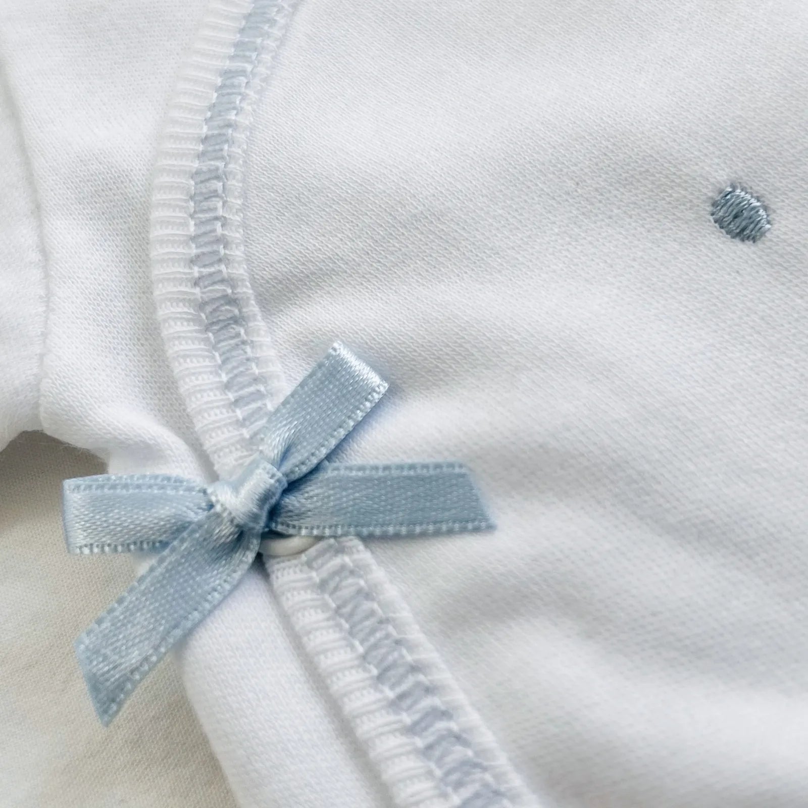 Pormenor de body de trespasse com collants com bordado pintas azul