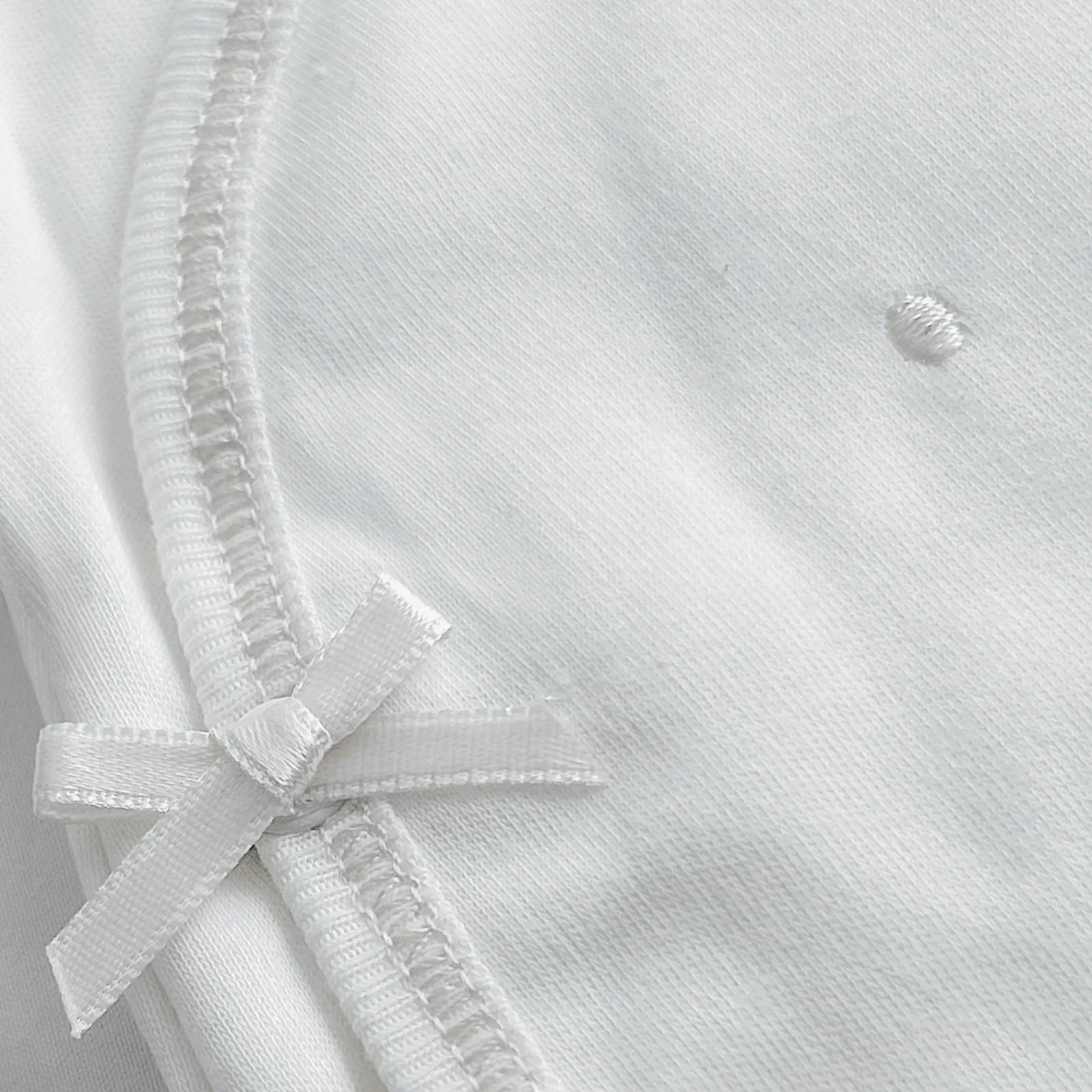 Pormenor de body de trespasse com collants com bordado pintas branco