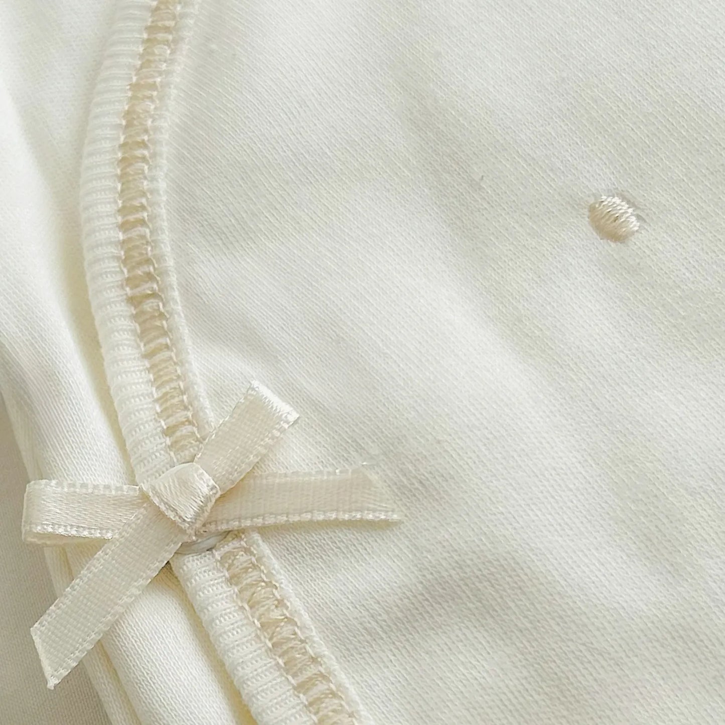 Pormenor de body de trespasse com collants pérola com bordado pintas