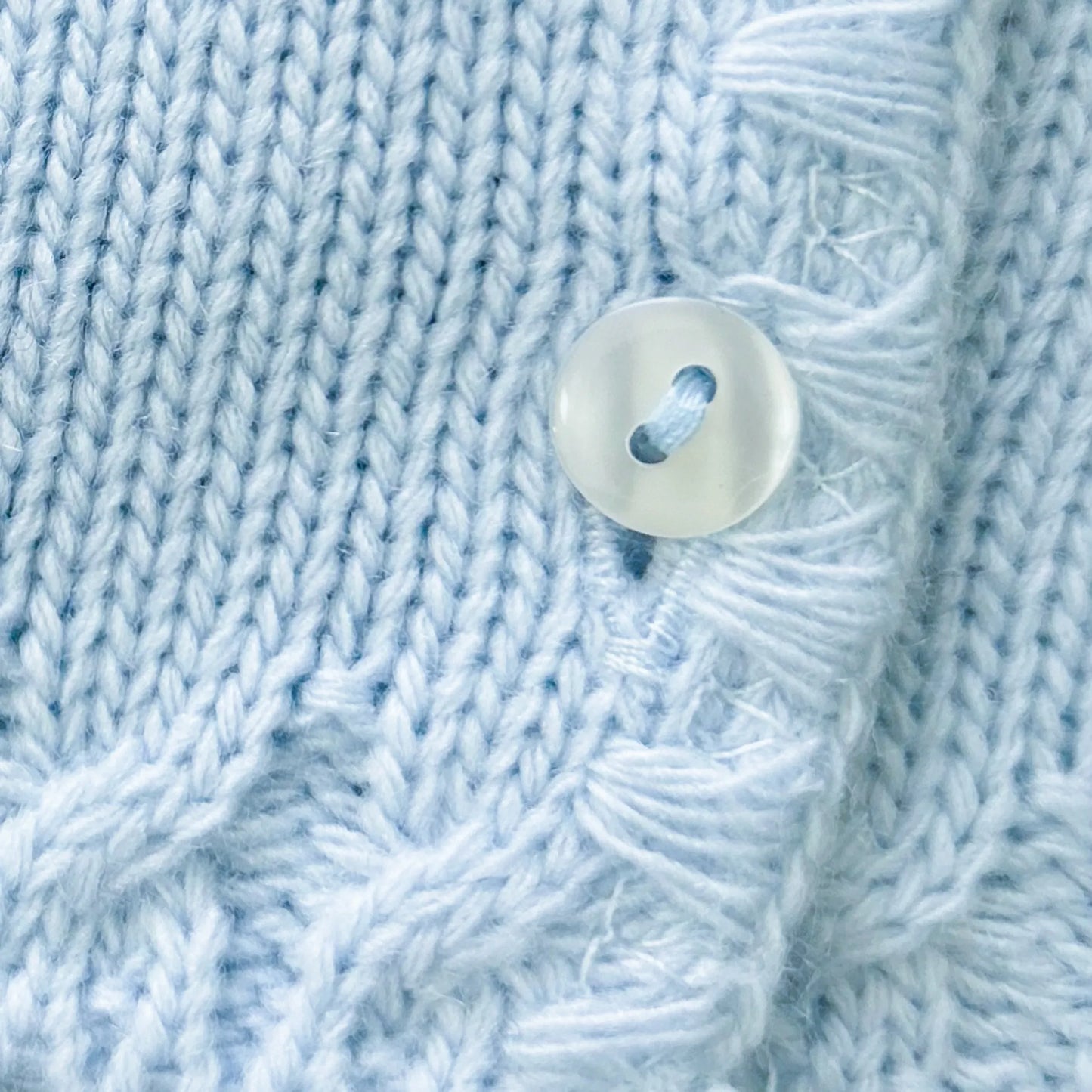 Pormenor de casaco em tricot com pormenores trabalhados nas extremidades azul