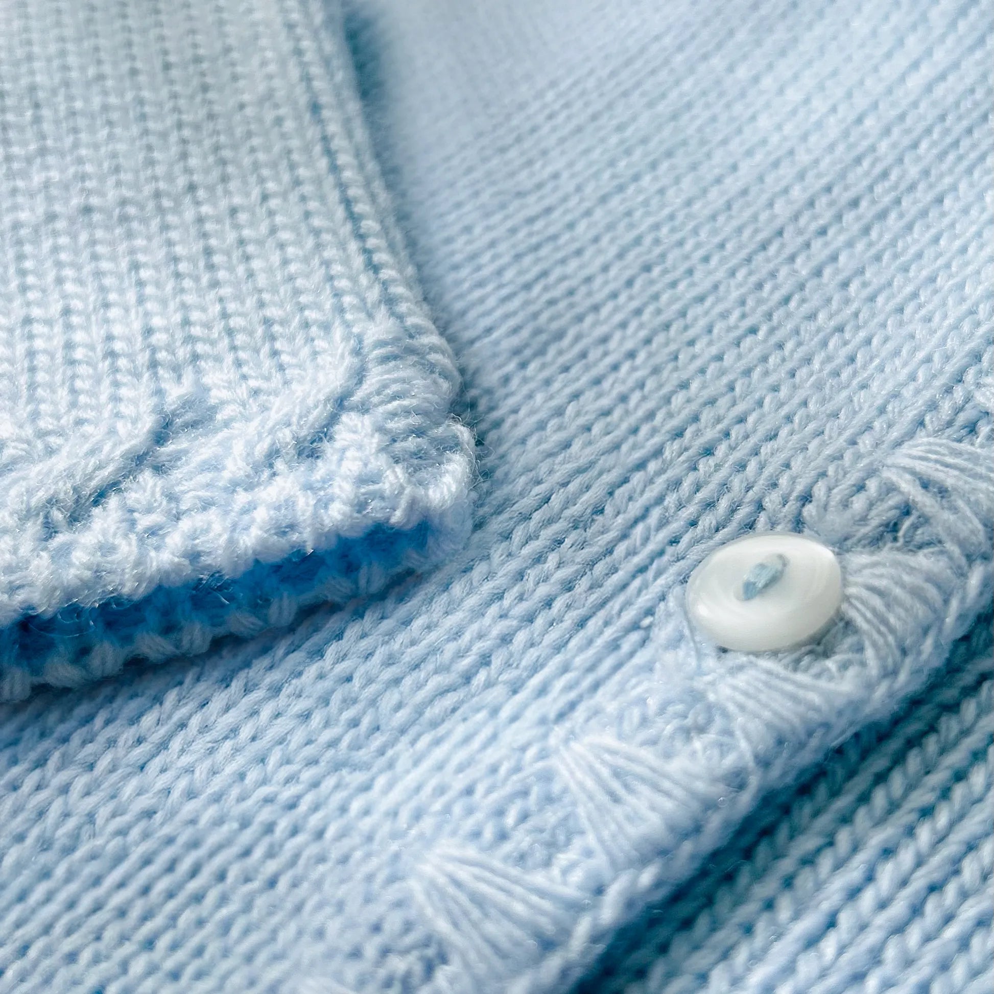 Pormenor de casaco em tricot com pormenores trabalhados nas extremidades azul