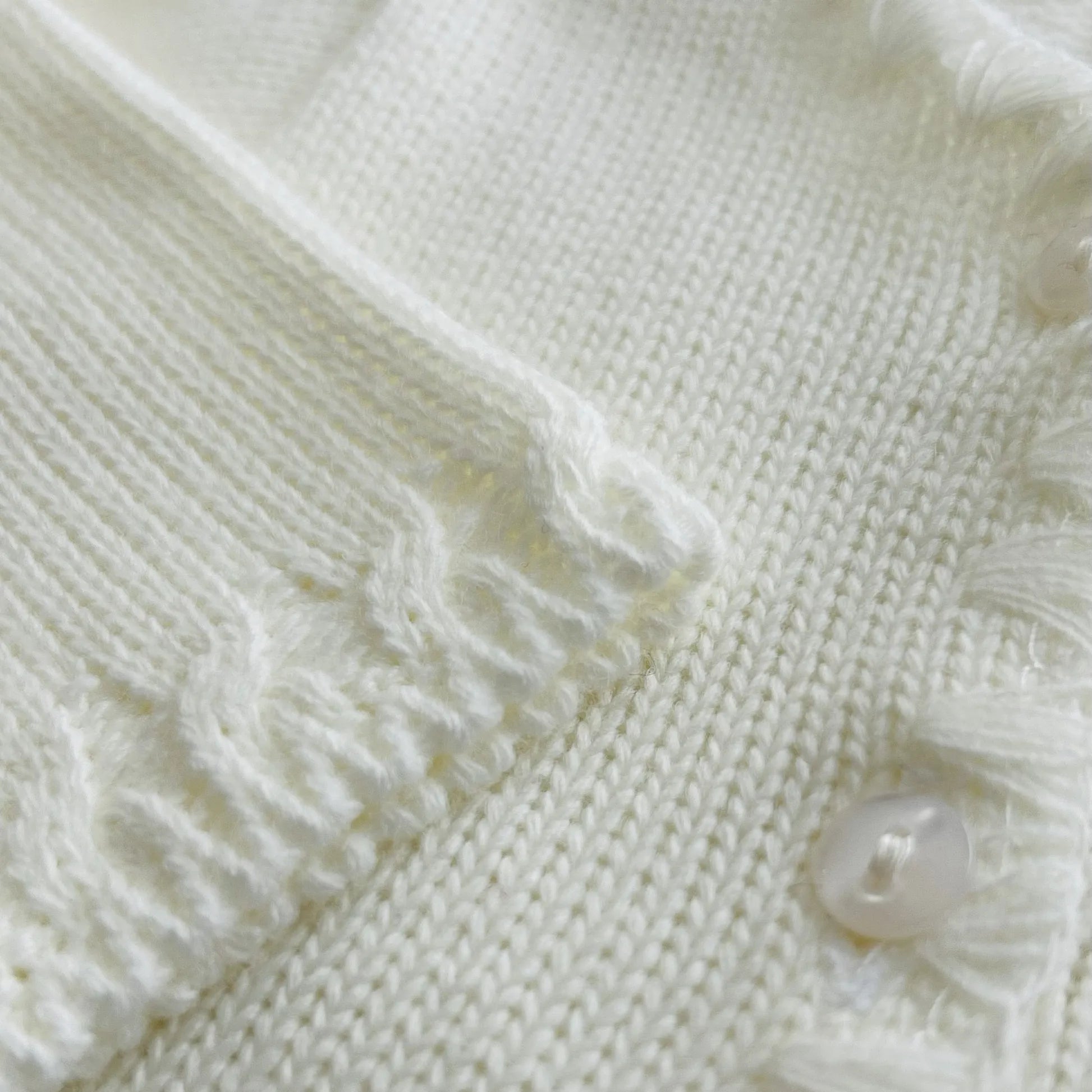 Pormenor de casaco em tricot com pormenores trabalhados nas extremidades pérola