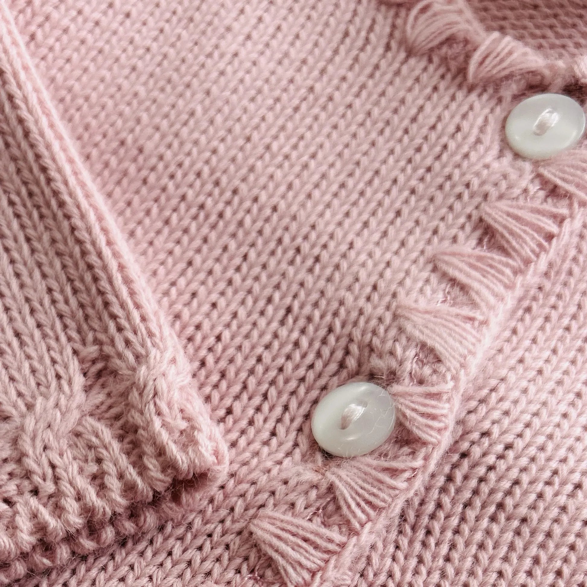 Pormenor de casaco em tricot com pormenores trabalhados nas extremidades rosa