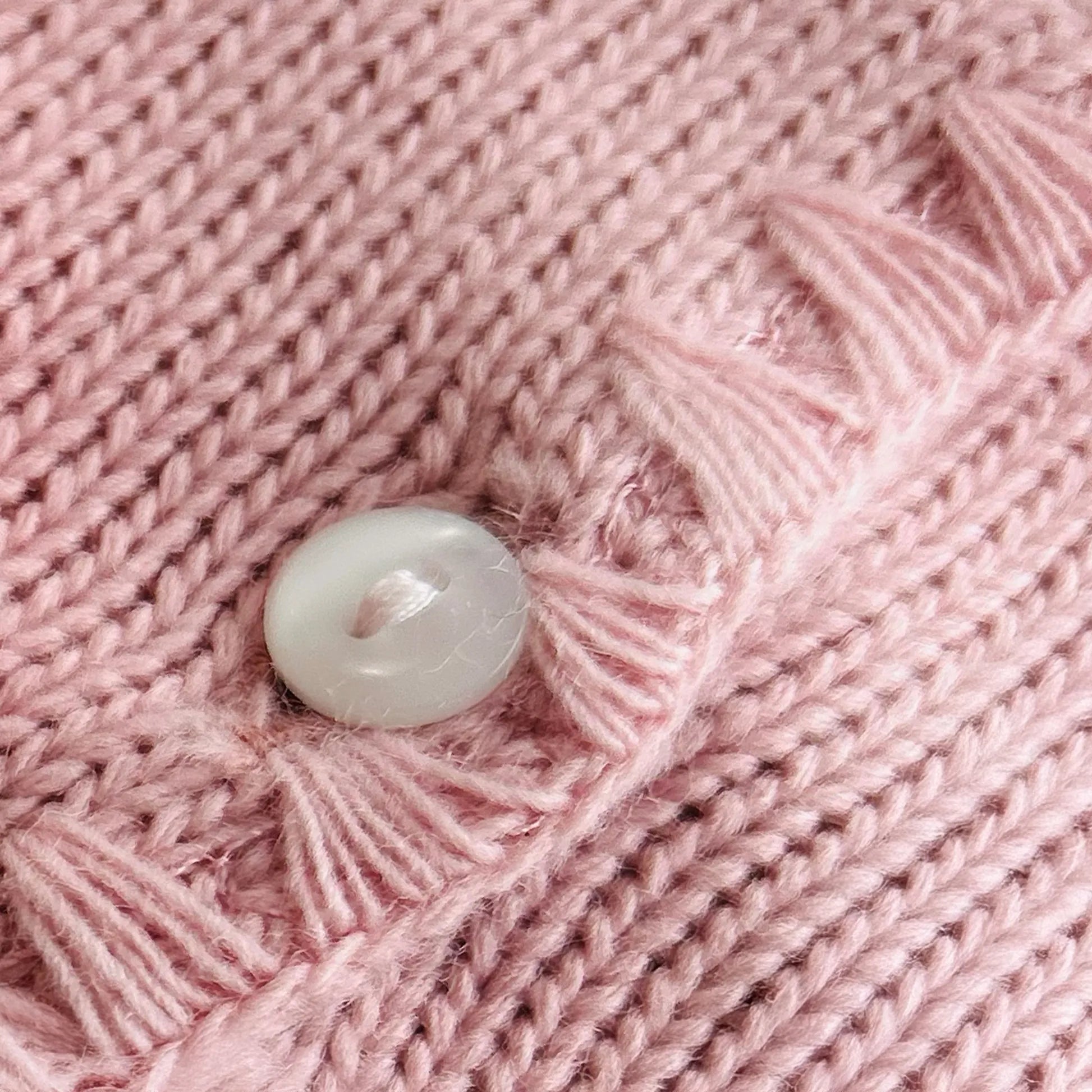 Pormenor de casaco em tricot com pormenores trabalhados nas extremidades rosa