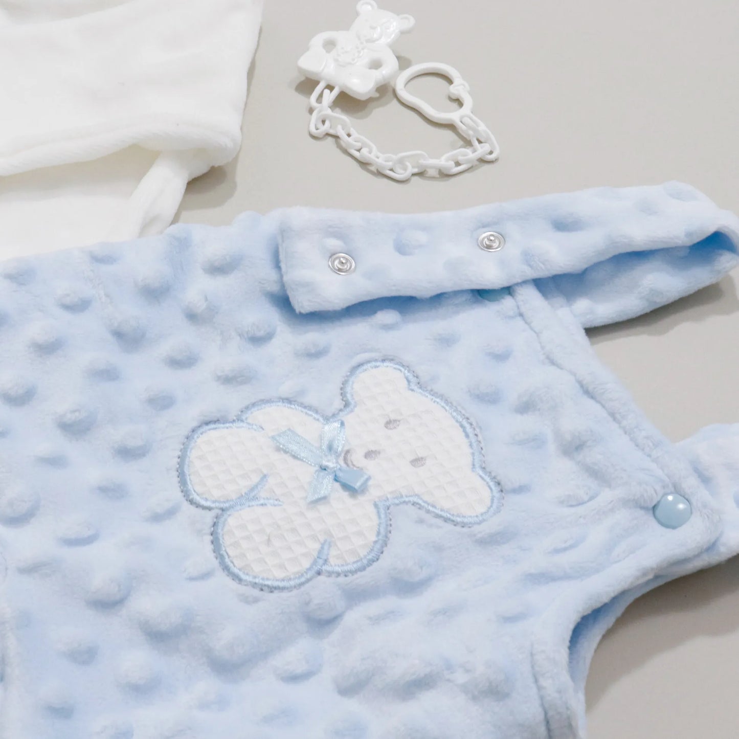 Pormenor de conjunto de jardineiras e camisola cardada com motivo ursinho waffle azul