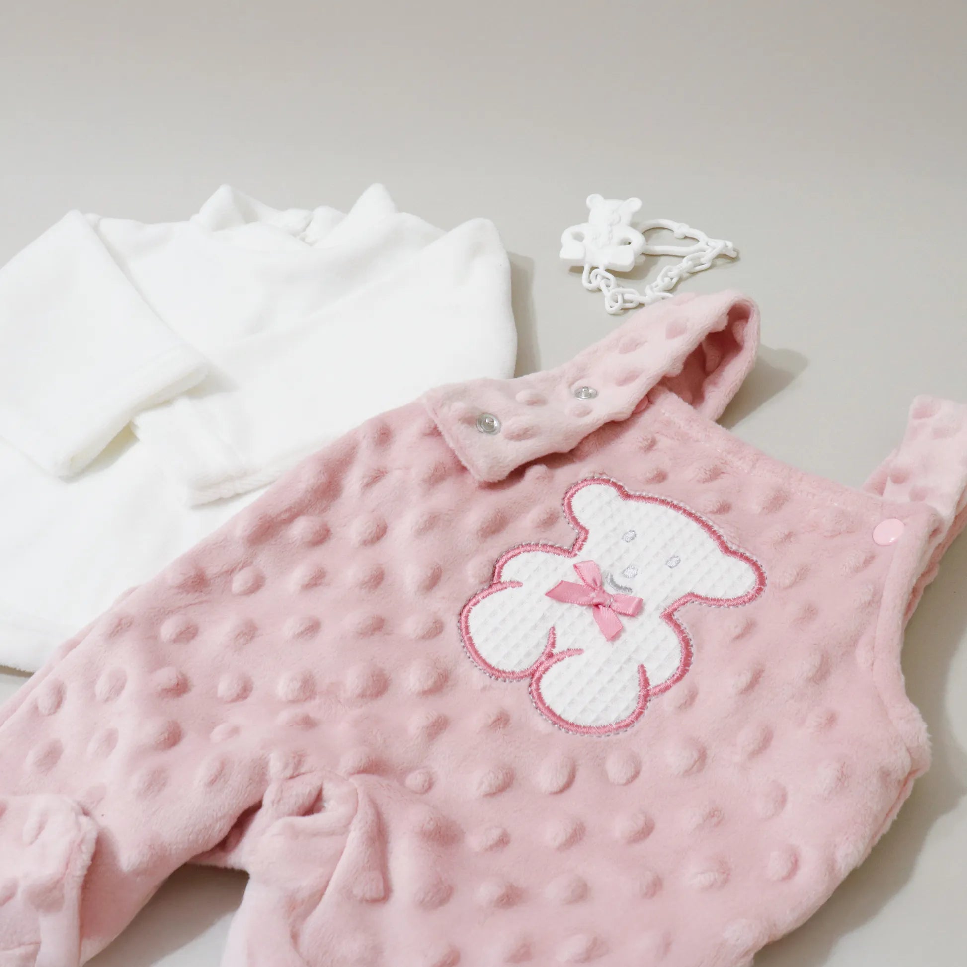 Pormenor de conjunto de jardineiras e camisola cardada com motivo ursinho waffle rosa