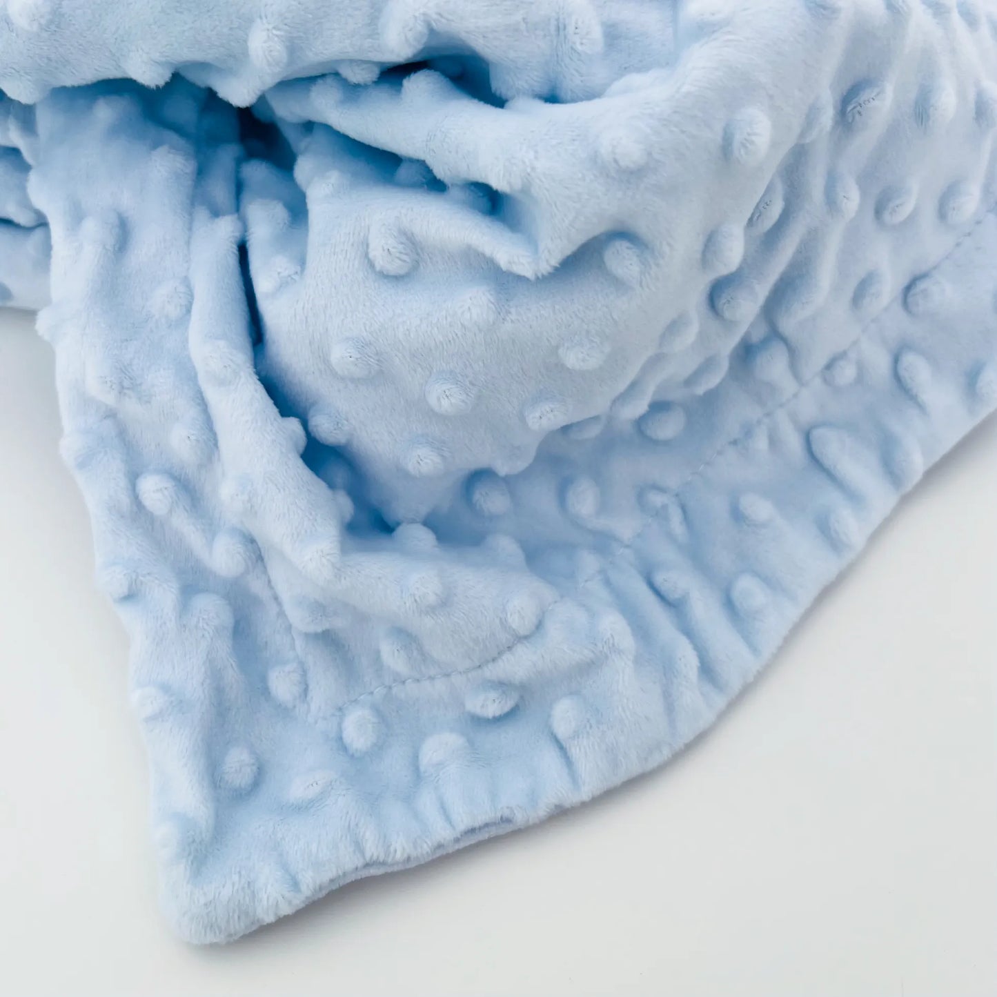 Pormenor de conjunto de manta e doudou ursinho com detalhes em relevo azul