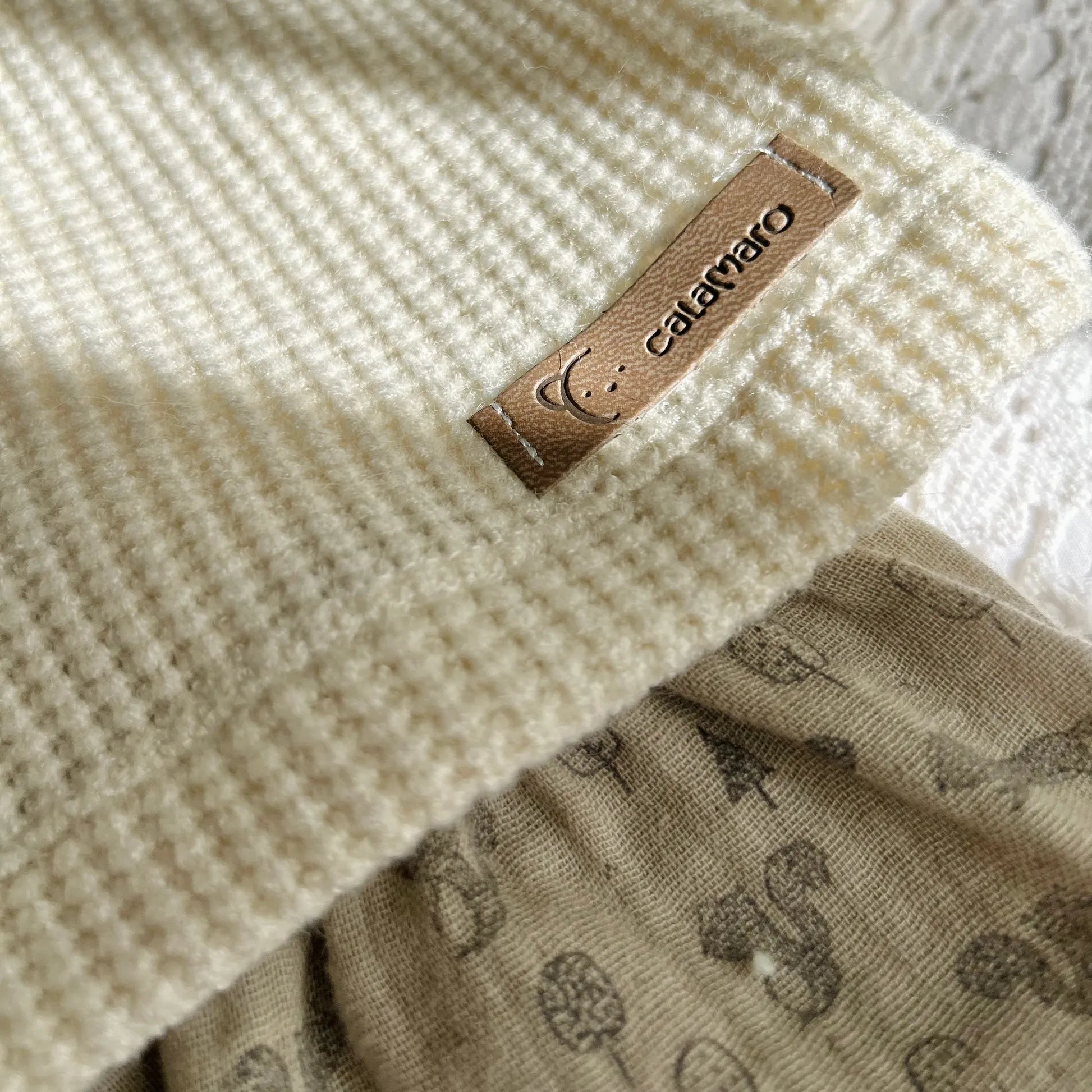 Pormenor de conjunto de menina de camisola pérola com folho na gola e tapa-fraldas cinza