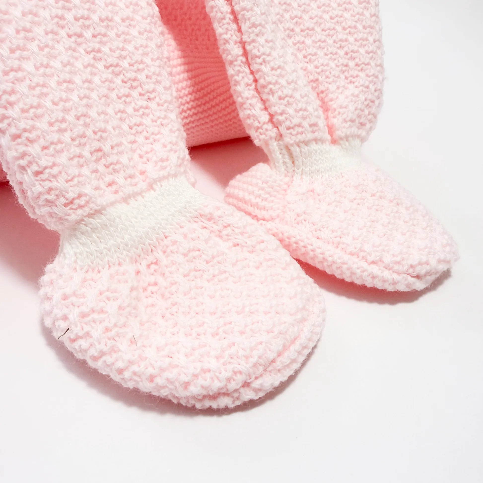 Detalhe de conjunto de menina de jardineira com laço, camisola e gorro com pompom em tricot rosa