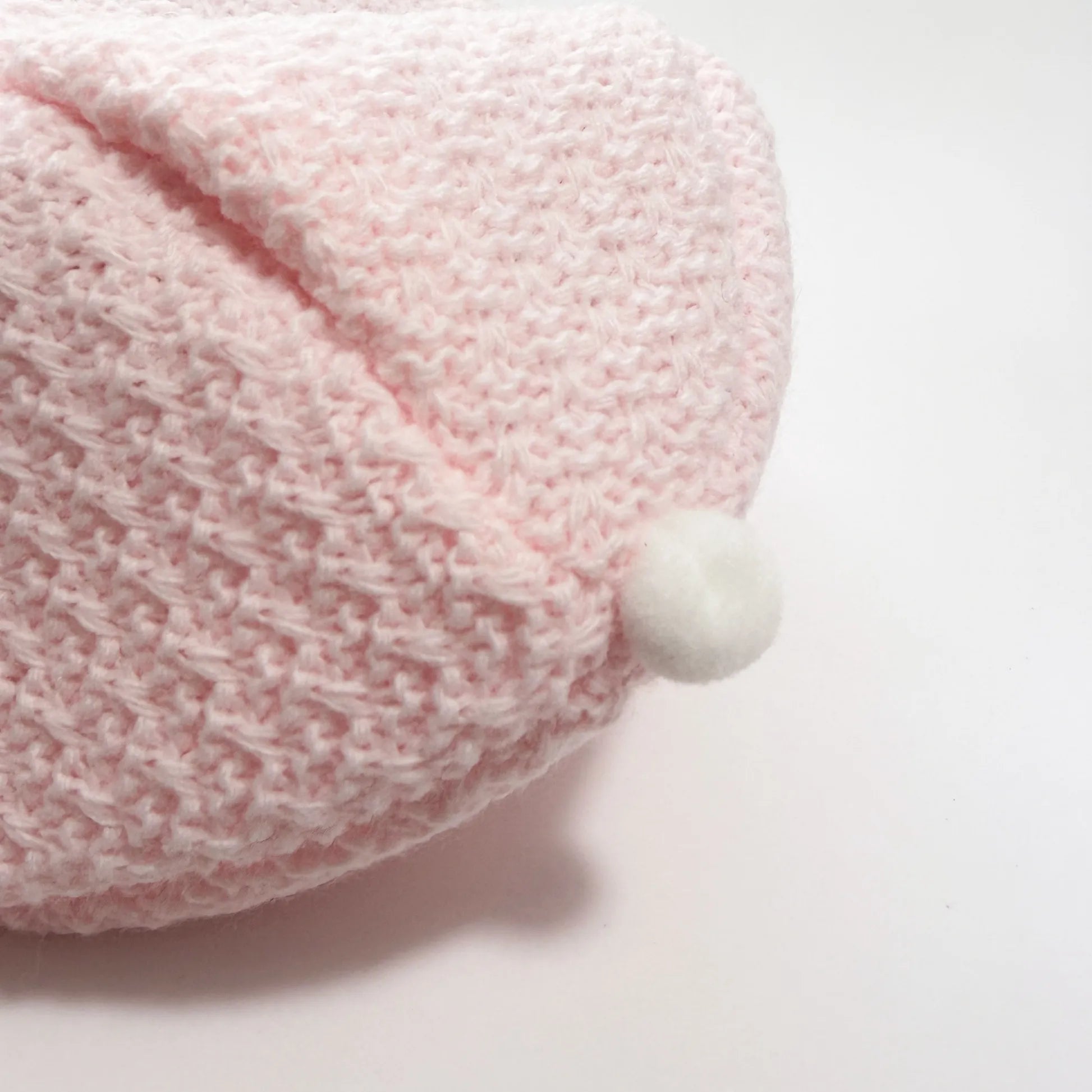 Detalhe de conjunto de menina de jardineira com laço, camisola e gorro com pompom em tricot rosa