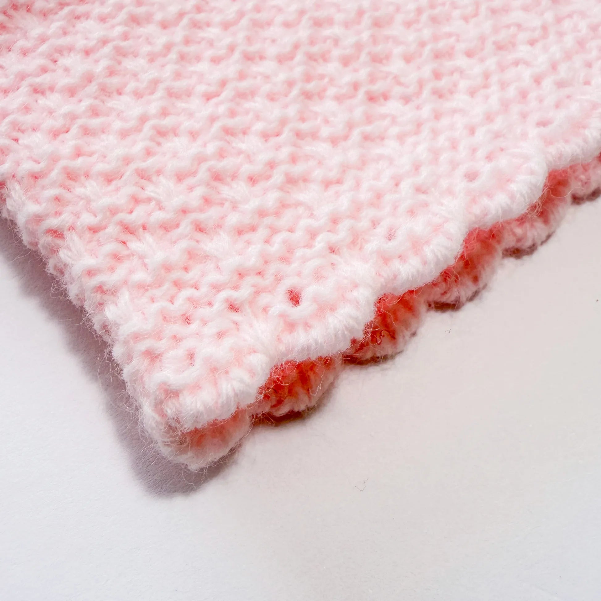 Detalhe de conjunto de menina de jardineira com laço, camisola e gorro com pompom em tricot rosa