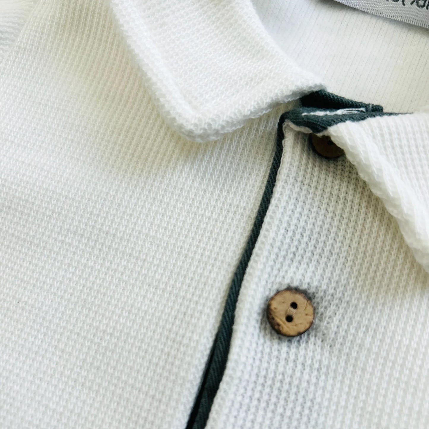 Pormenor de conjunto de menino de camisola cru com botões e calção de tecido verde