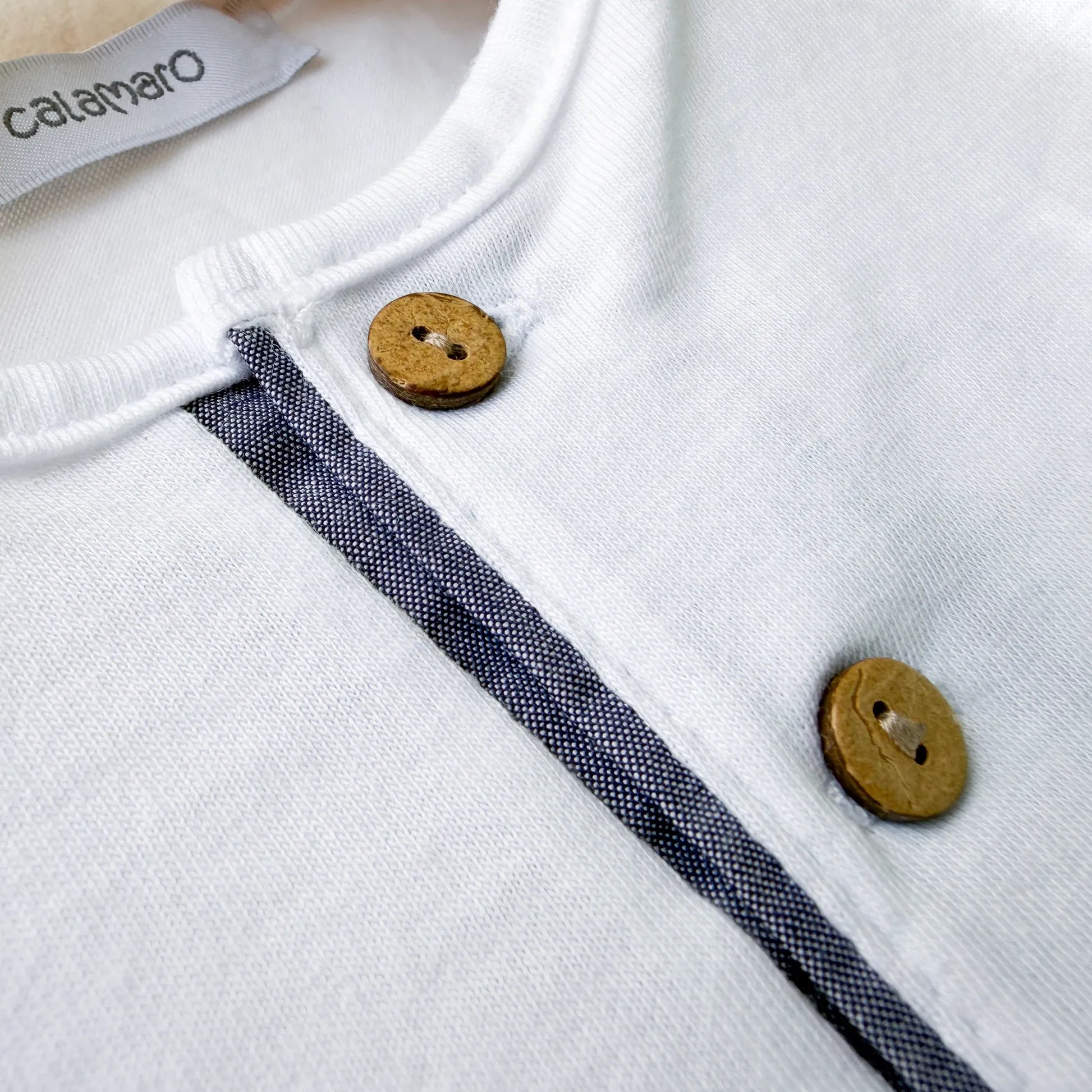 Pormenor de conjunto de menino de T-shirt com botões e calção de tecido marinho