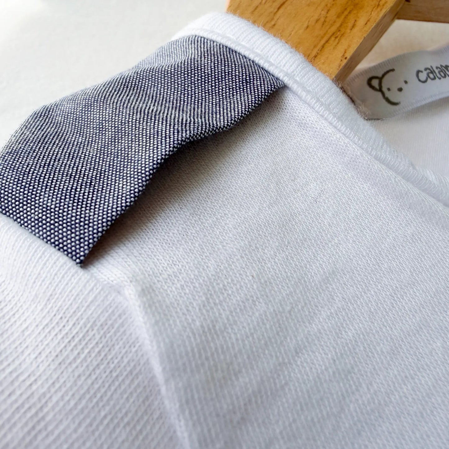 Pormenor de conjunto de menino de T-shirt com botões e calção de tecido marinho