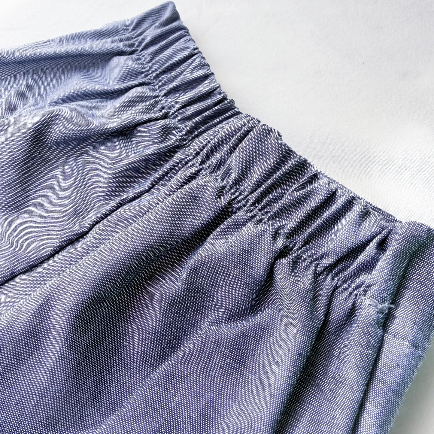 Pormenor de conjunto de menino de T-shirt com botões e calção de tecido marinho