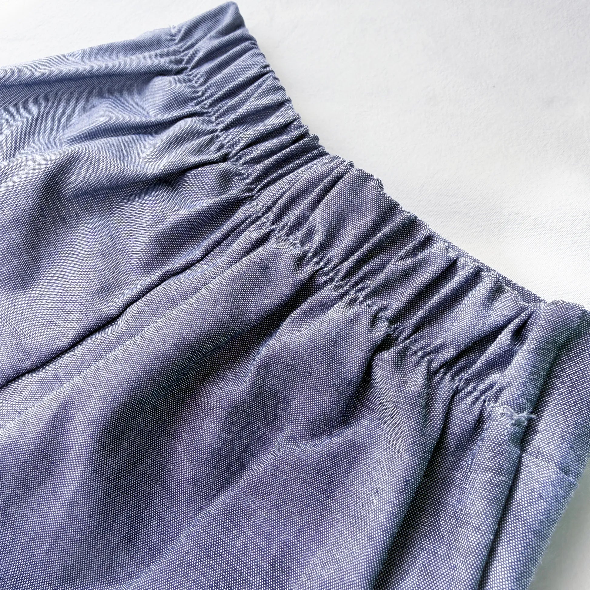 Pormenor de conjunto de menino de T-shirt com botões e calção de tecido marinho