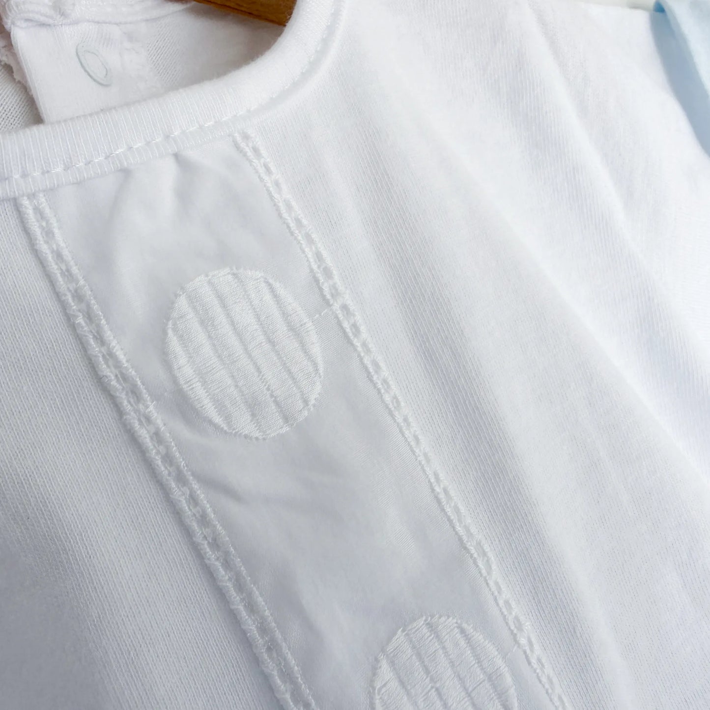 Pormenor de conjunto de menino de T-shirt com faixa decorativa bordada e tapa-fraldas azul