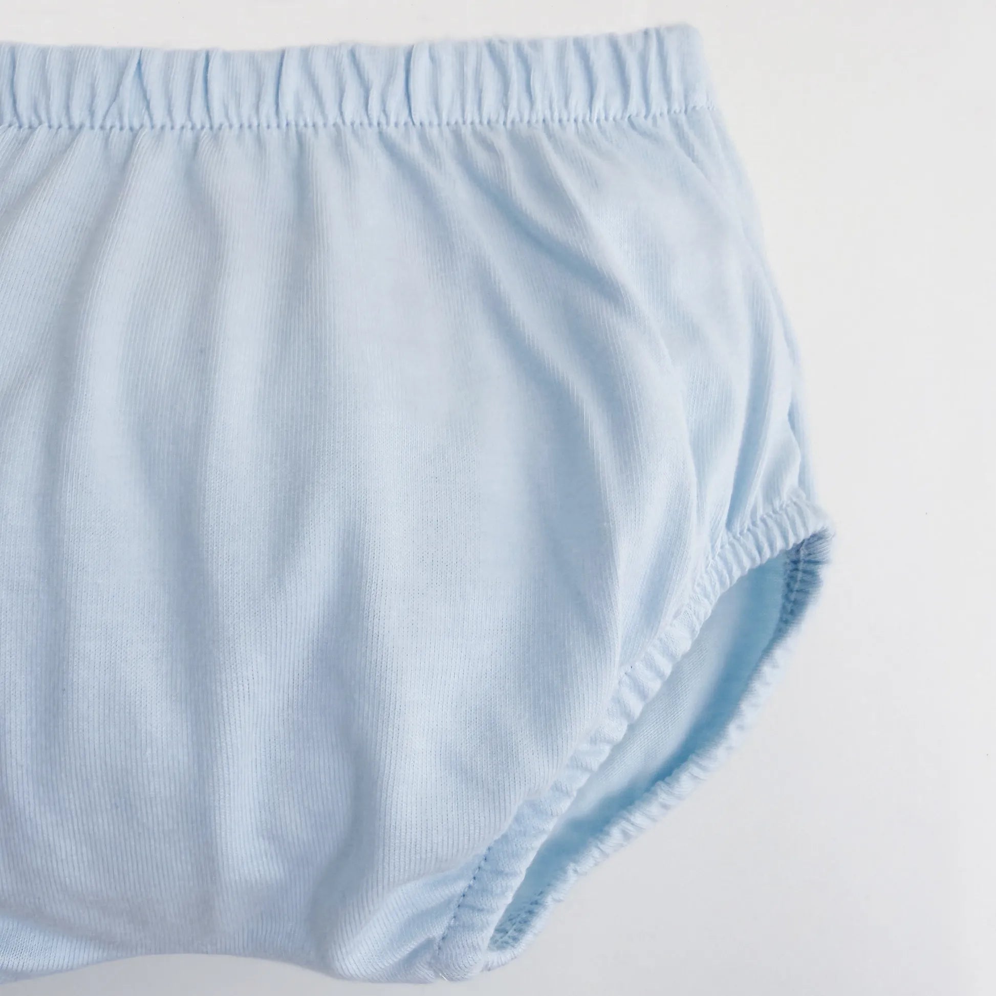 Pormenor de conjunto de menino de T-shirt com faixa decorativa bordada e tapa-fraldas azul