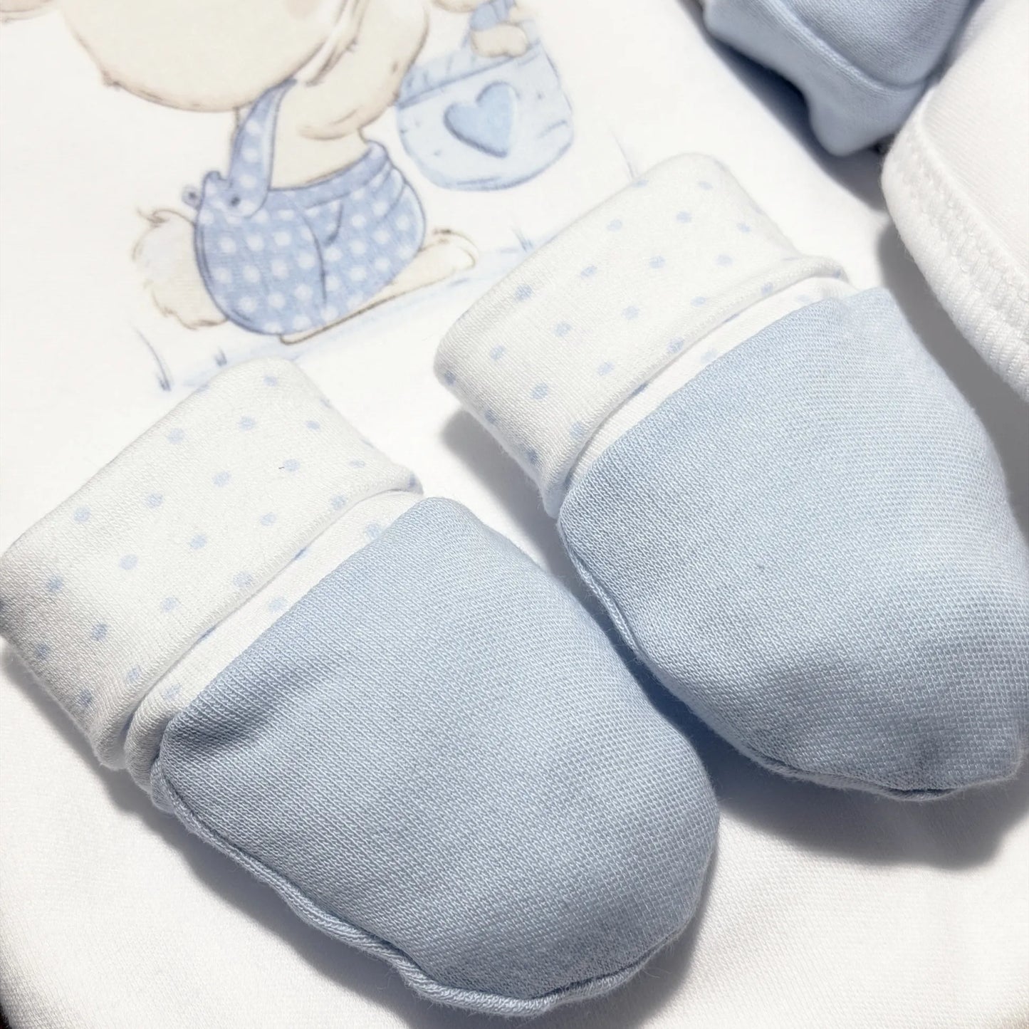 Pormenor de conjunto de primeira roupinha com motivo coelhinho na cesta azul