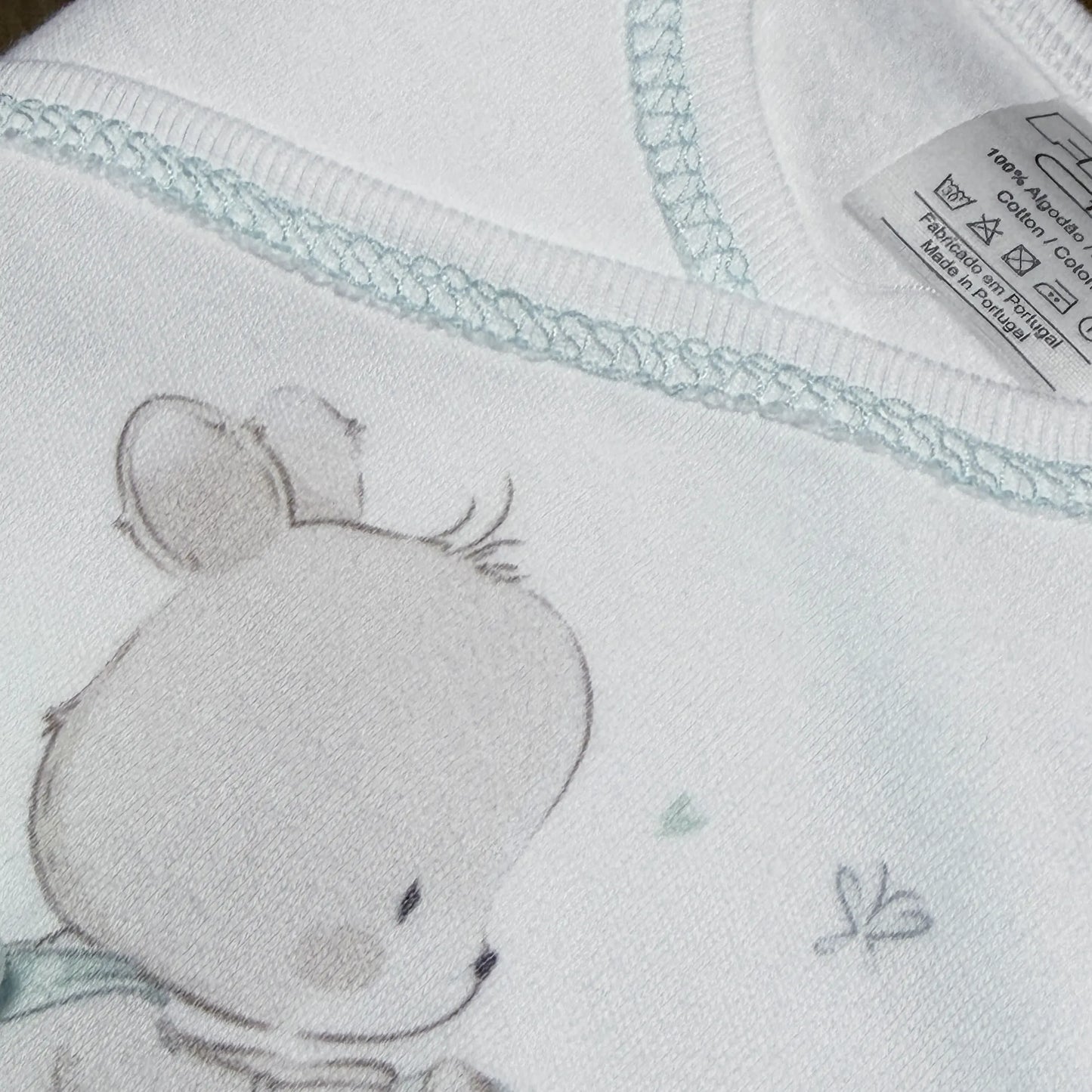 Pormenor de conjunto de primeira roupinha com motivo coelhinho na cesta verde